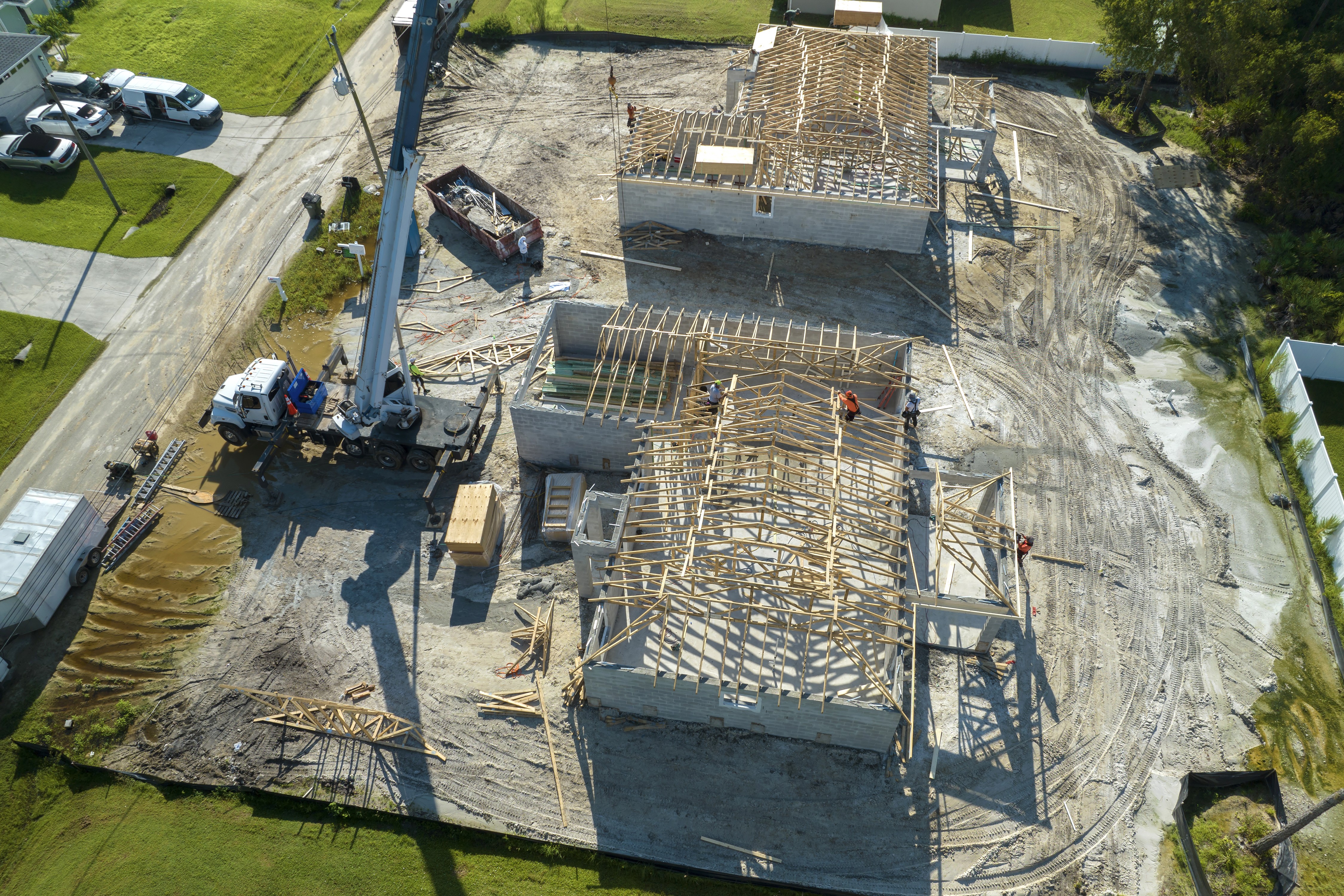 Aerial view of active construction site with crane and building frame under clear blue sky