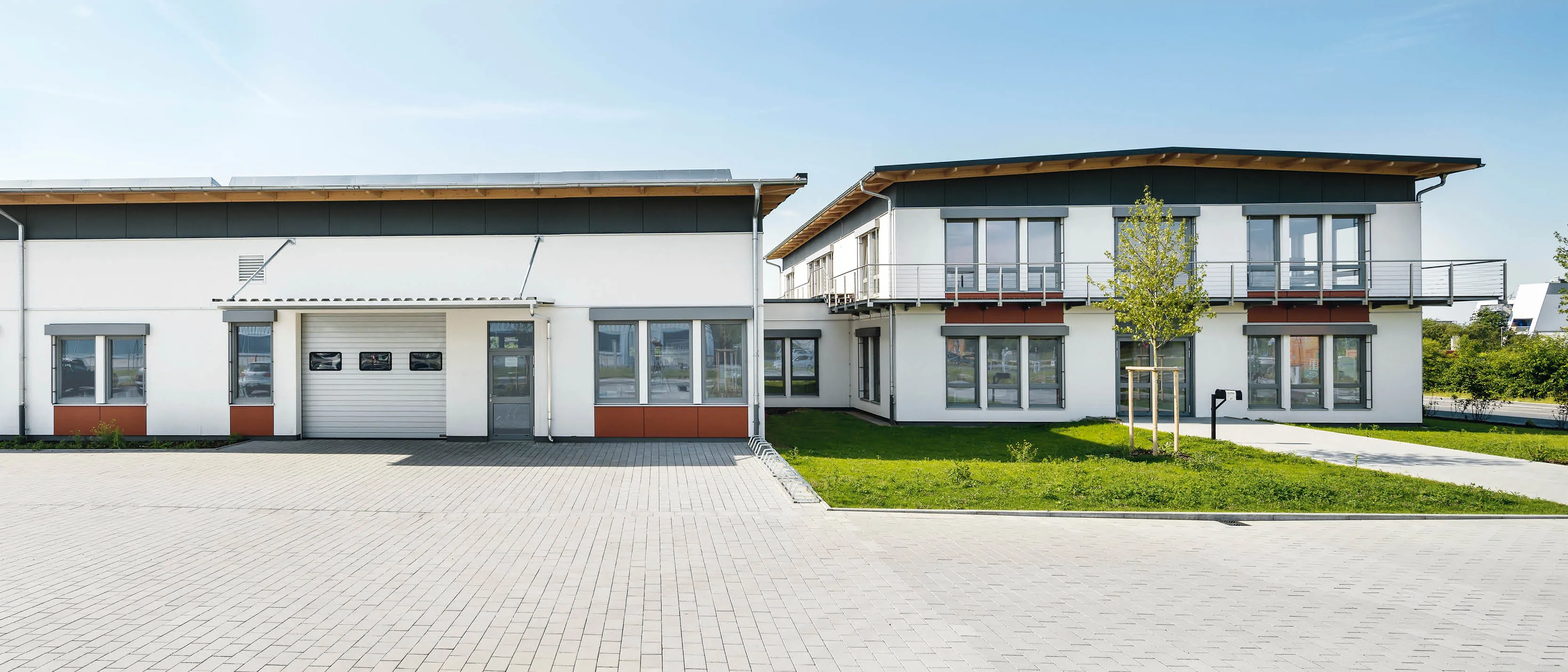 Moderne Produktions- und Bürogebäude mit weißen Fassaden, hellgrauen Fensterelementen und Flachdächern.
