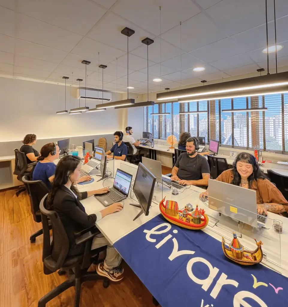 Equipe da Livare Viagens trabalhando em escritório moderno, com colaboradores em estações de trabalho e ambiente corporativo organizado