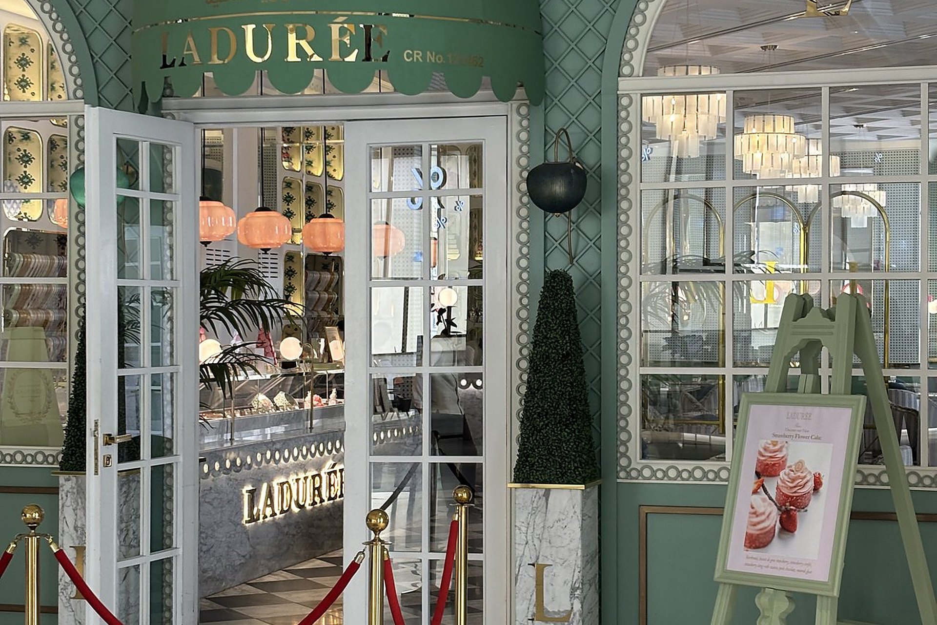 La façade vert d'eau de la boutique Ladurée de Place Vendôme, à Lusail, avec sa marquise et ses lampadaires noirs