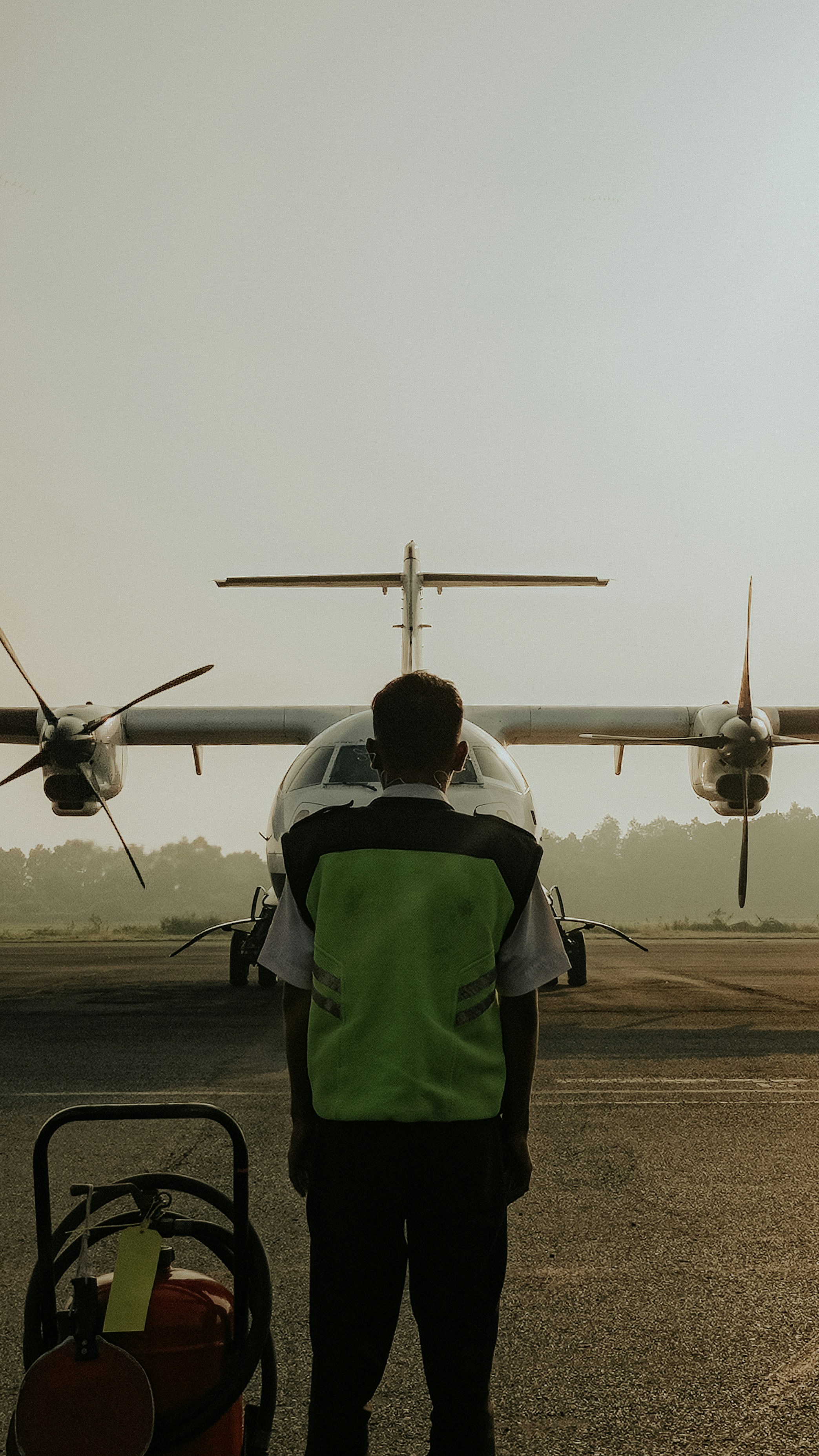 A ground crew member stands before a plane.