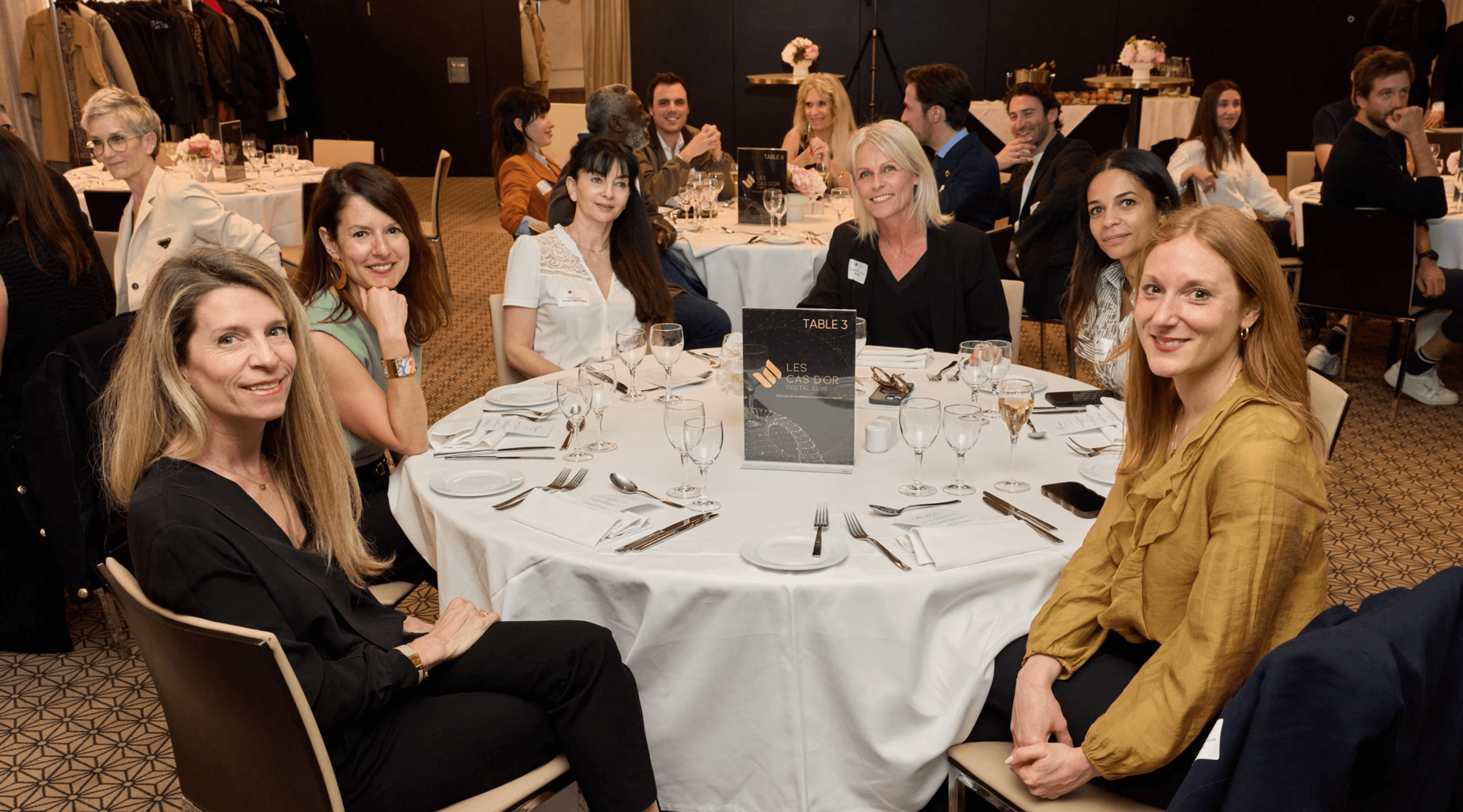 Man in a white shirt reclines in a chair on a red carpet, talking on the phone. Scattered papers surround him, conveying stress or disarray.