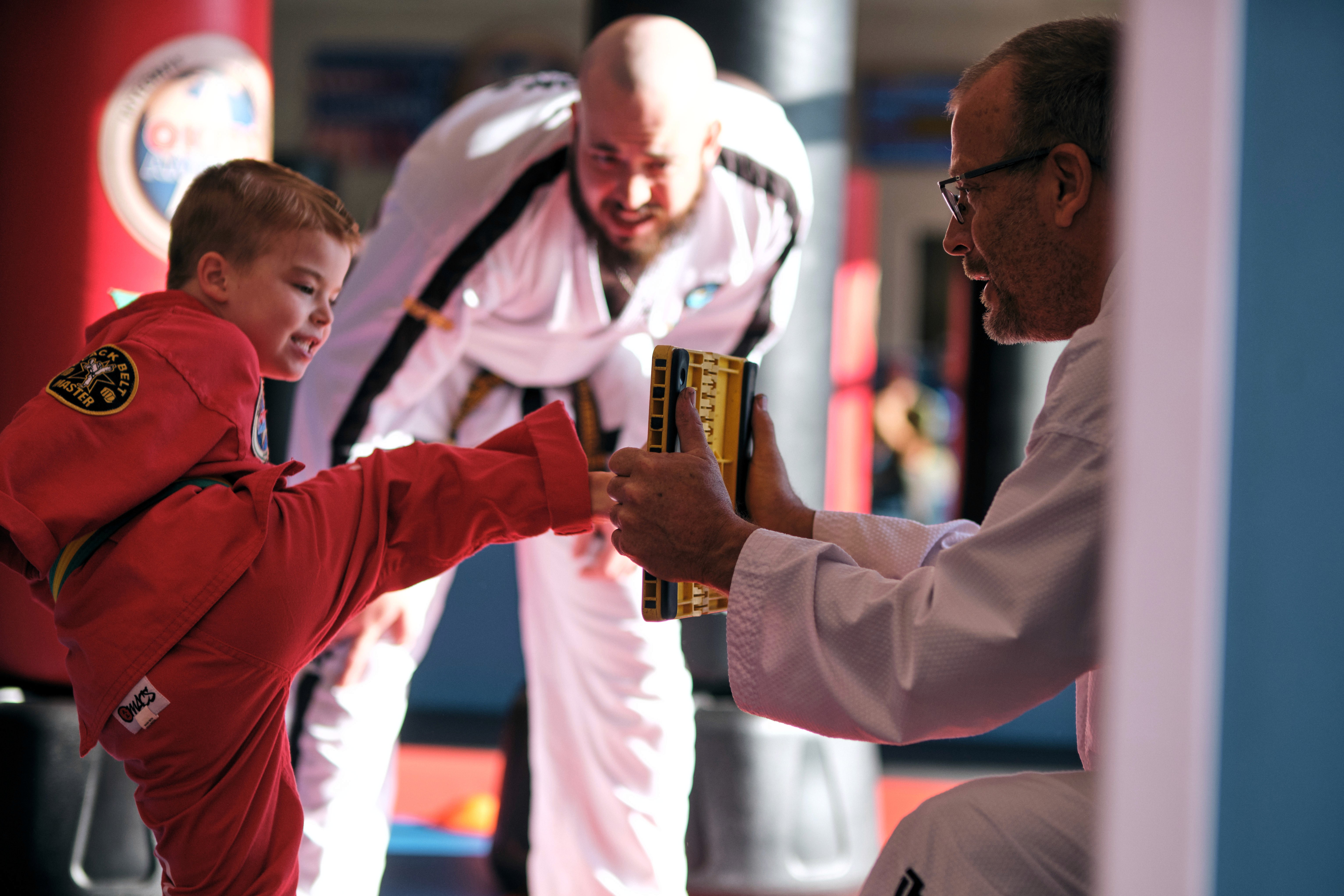 Student kicking into a board with Instructor in the background