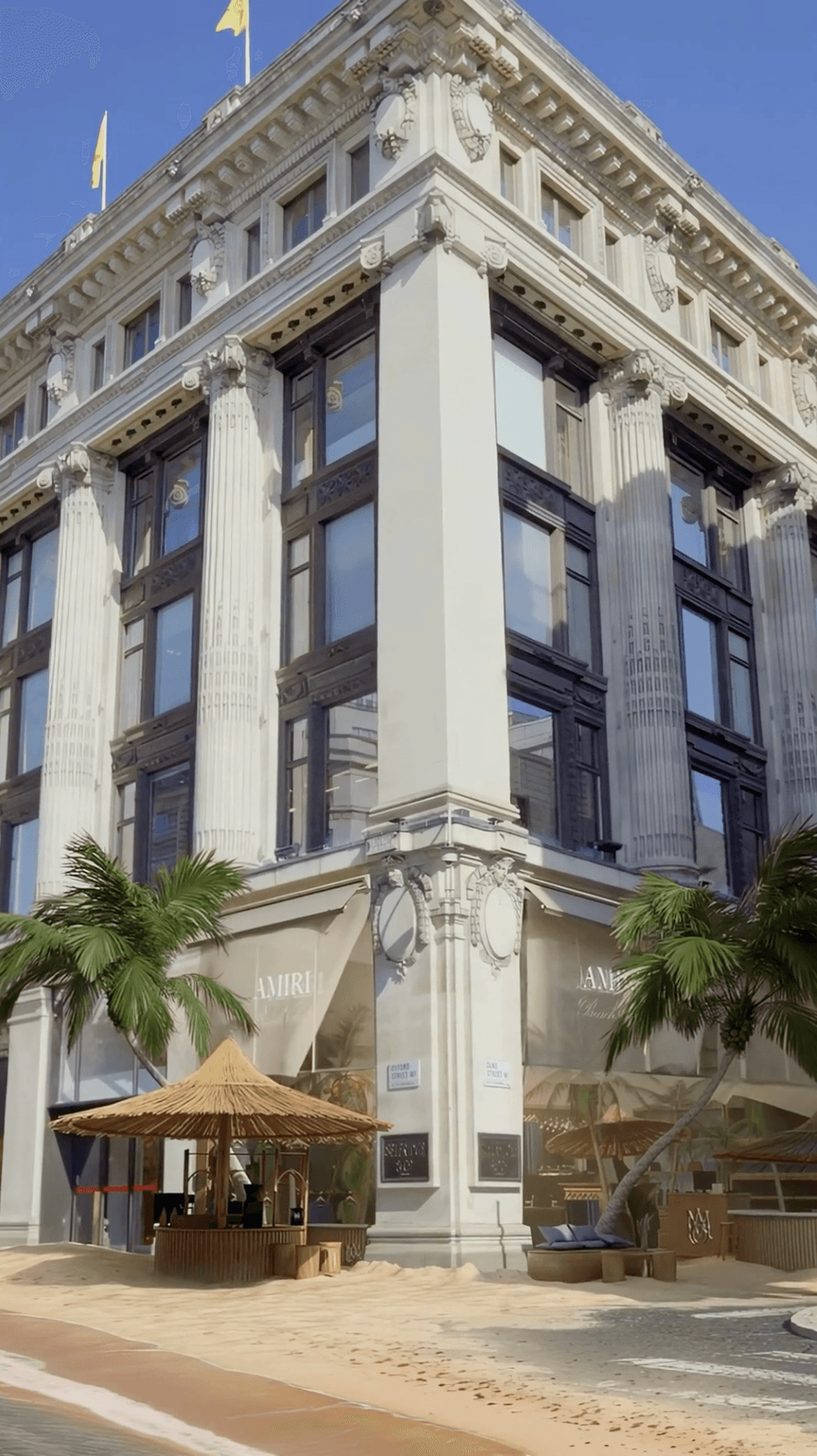 A low-angle shot of a grand white building facade with classical columns and tropical palm trees