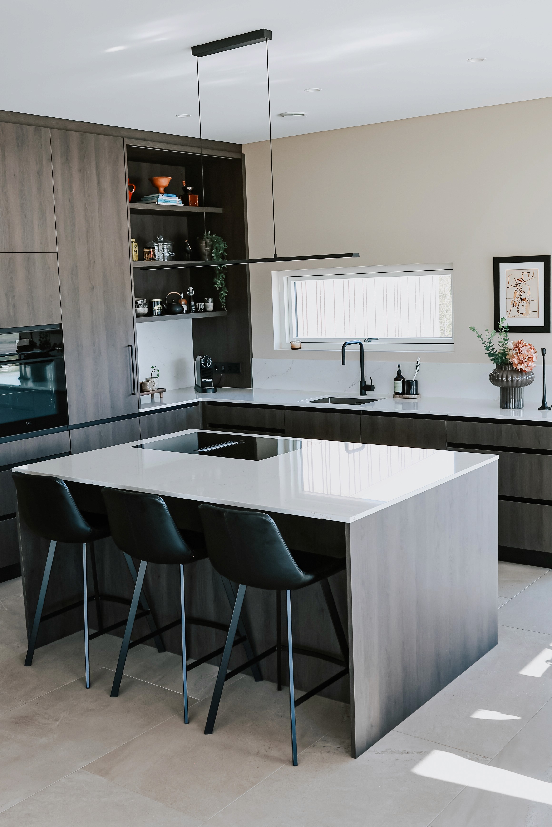 Kona halla sér á Mont Blanc quartzite eldhúseyju með dökkum viðarskápum í bakgrunni