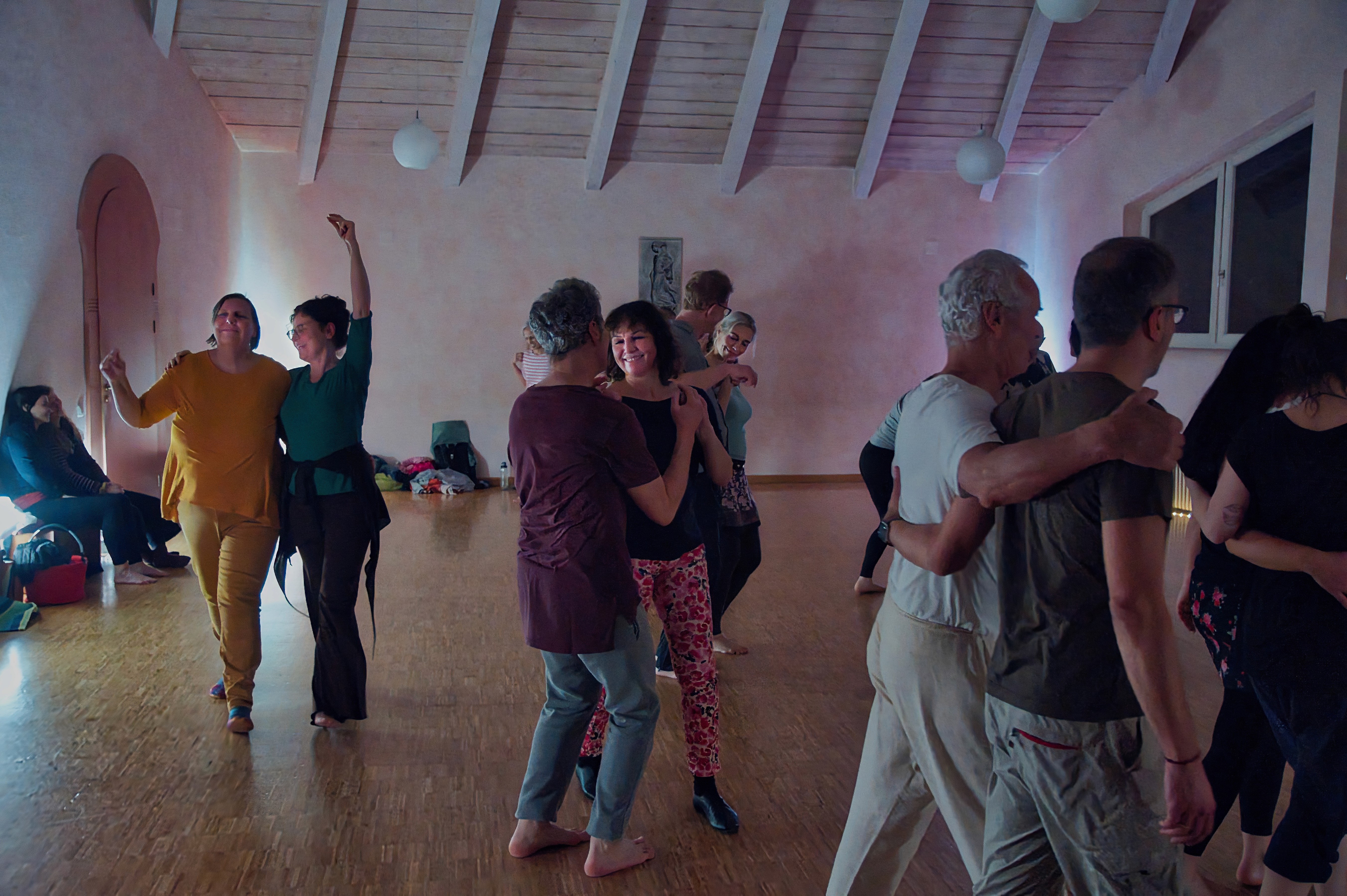 A serene and elegant spa space with wooden reclining chairs and white cushions. Golden sunlight filters through a cascading water feature, creating a peaceful atmosphere. Tropical plants and candles add to the relaxing ambiance.