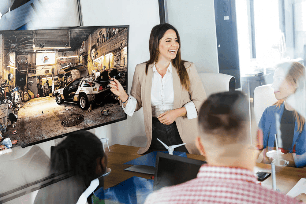 Participants lors d'un team building dans un bureau, jouant au jeu PopCorn Garage avec le décor projeté sur un écran TV.