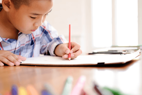 Child completing a writing task during a cognitive and learning assessment session