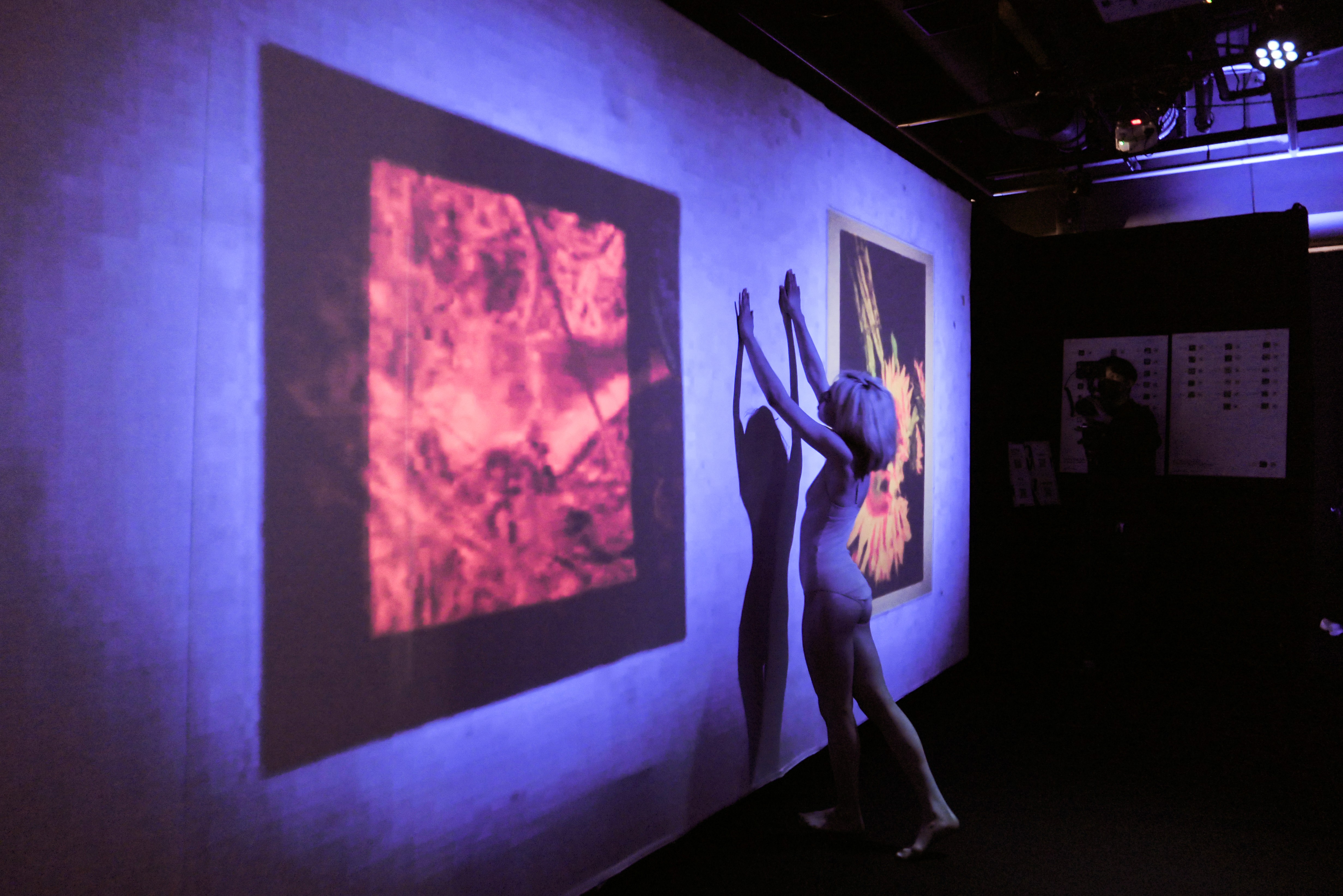 A dark museum hall with people viewing a Rembrandt painting