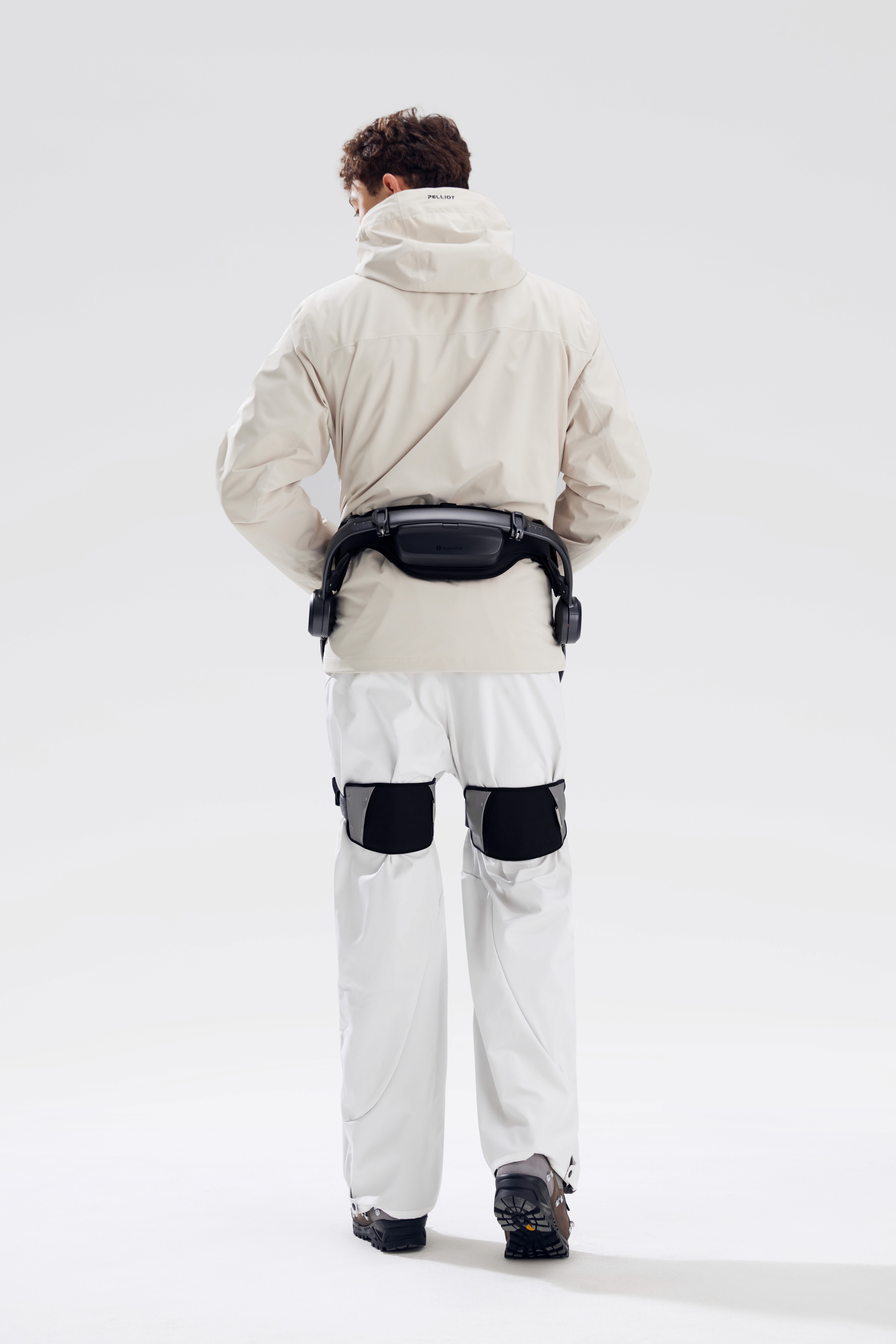 Utilisateur vu de dos portant l’exosquelette actif Hypershell X Pro à la taille et aux cuisses, marchant confortablement en environnement extérieur.