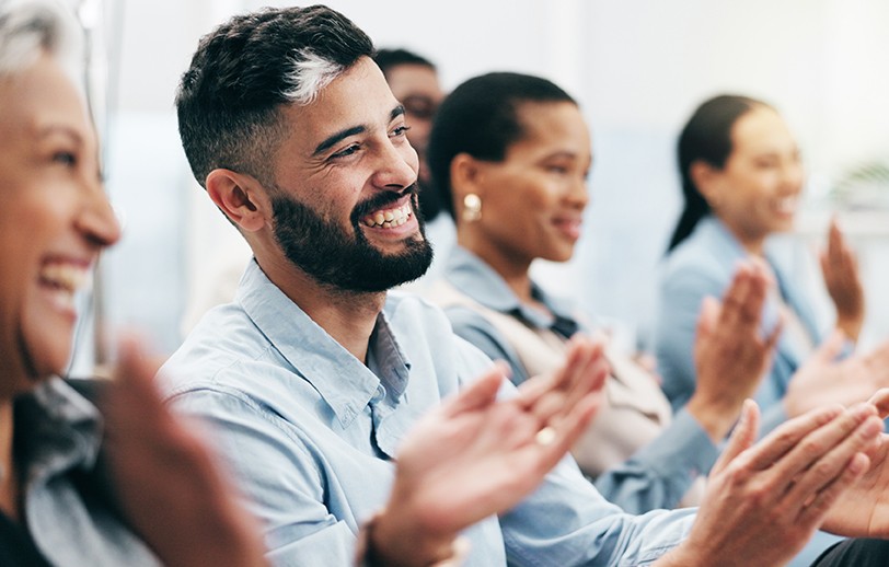 Mixed race group of men and women all applauding