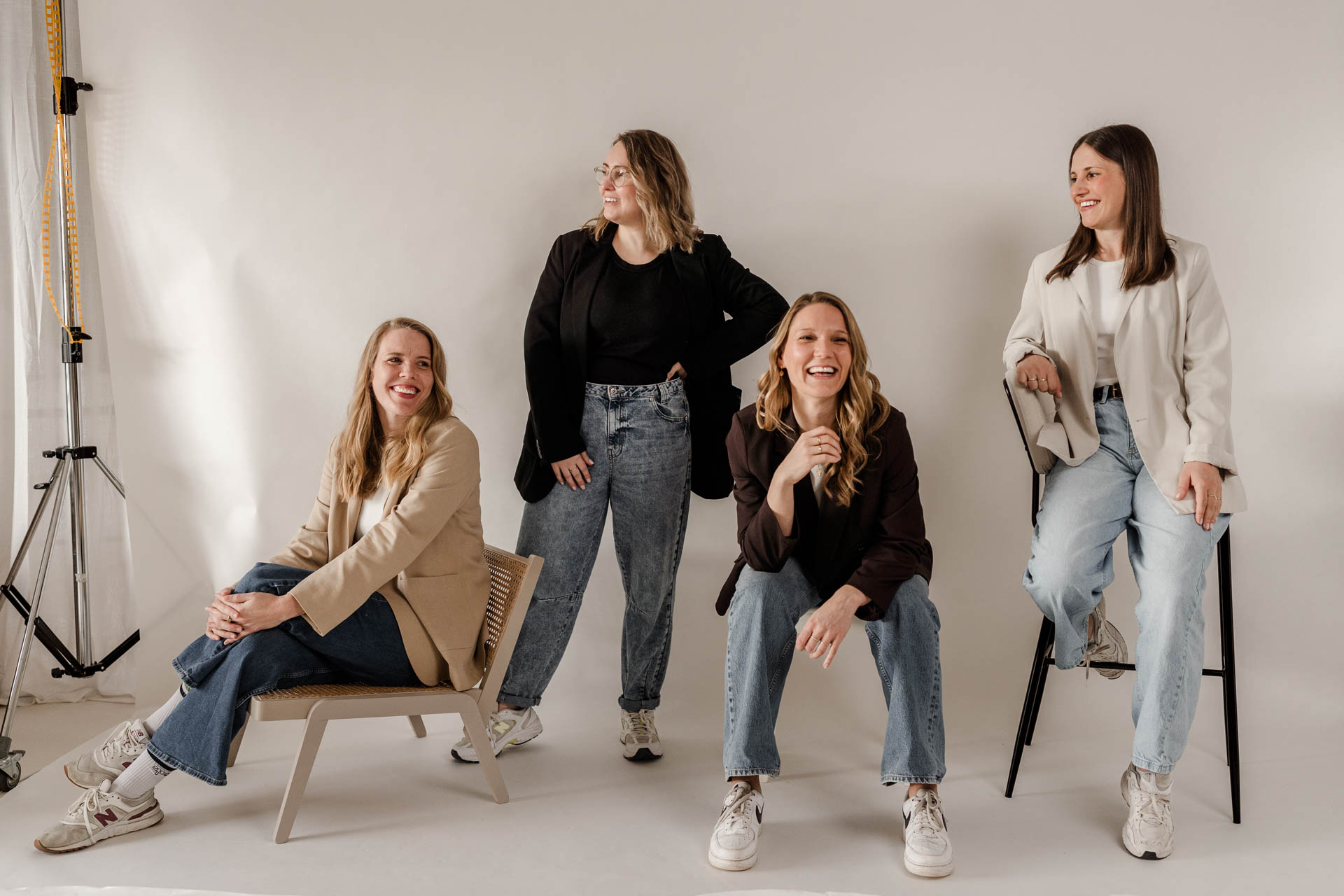 Portrait der vier Frauen von OHNORD studio für Websiten und Branding, zum Teil sitzend und stehend, locker in die Kamera lächelnd