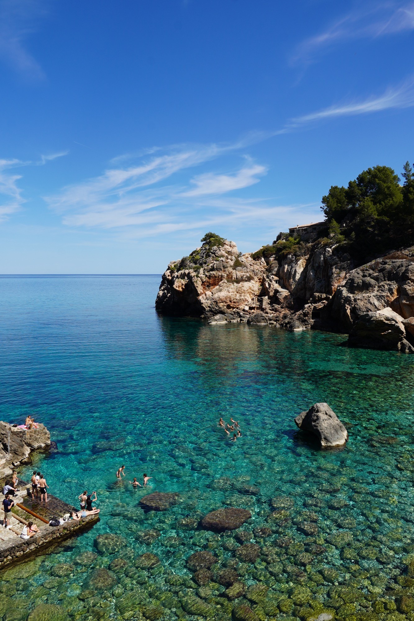 The rocky shoreline of Cala Deià beneath the cliffs