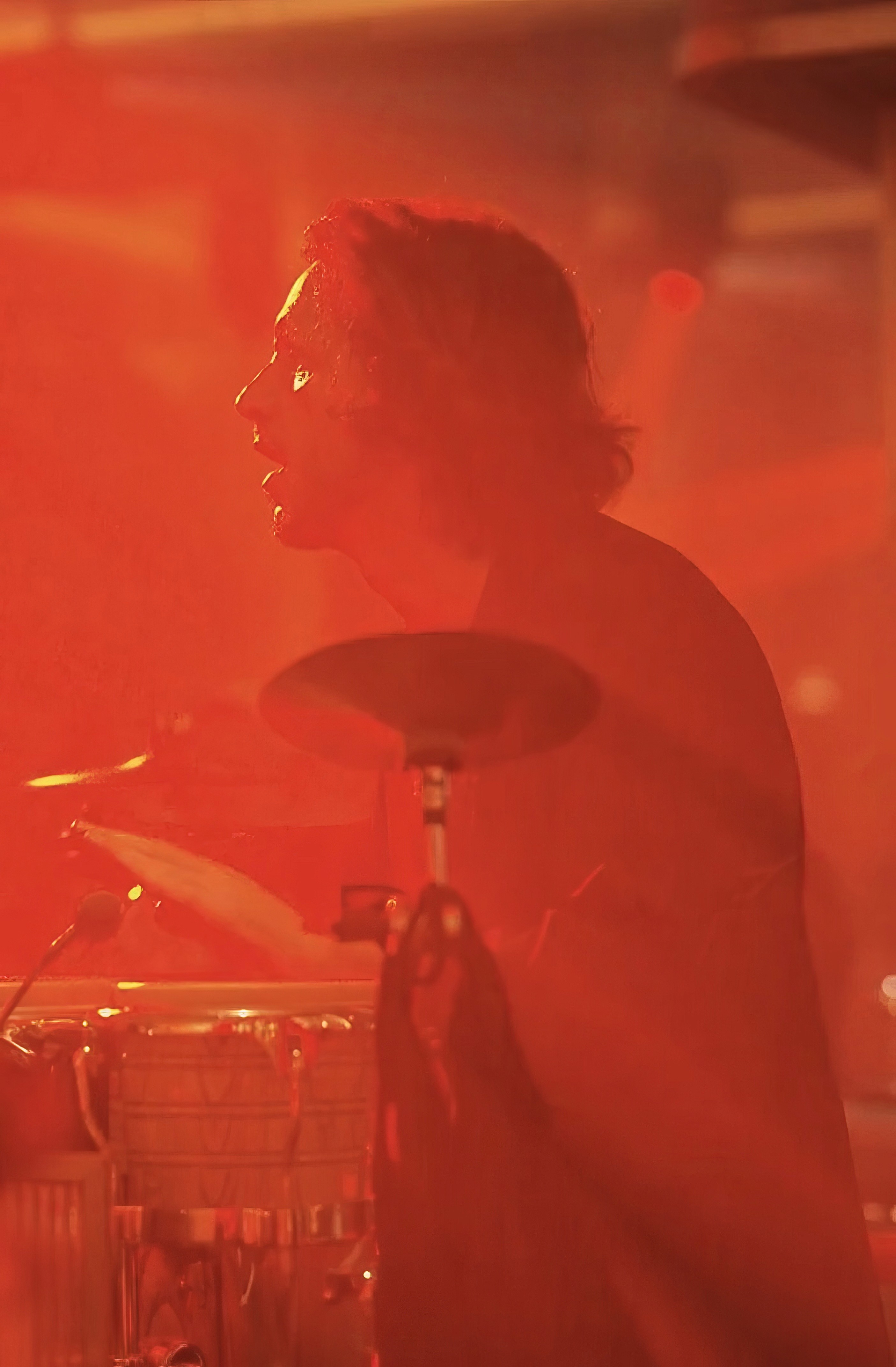 Bride sitting on ground against wall, groom standing nearby
