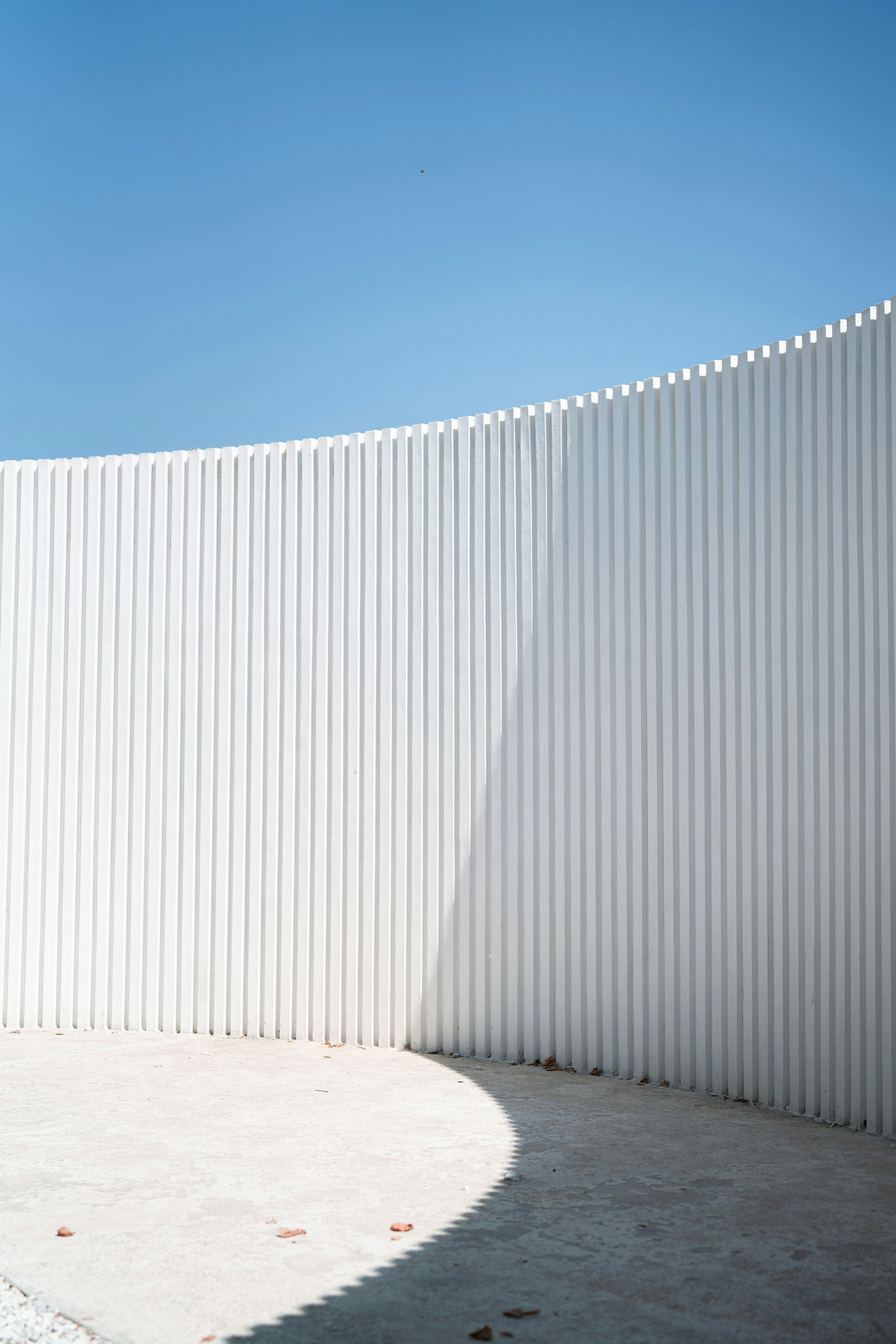 White, curved wall against a vibrant blue sky.