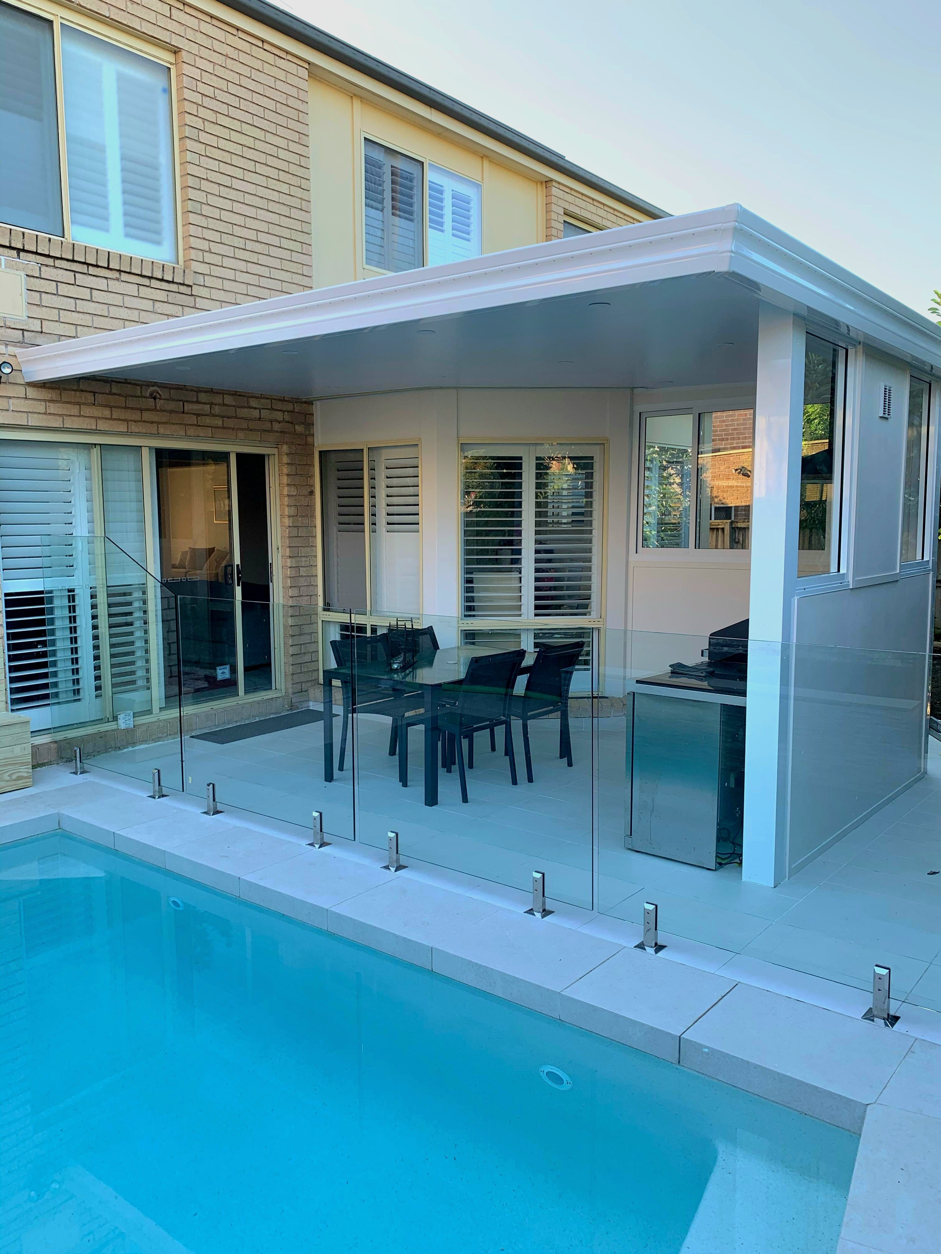 Modern outdoor pergola with enclosed pergola by the pool, featuring glass fencing, dining area, and durable low-maintenance design