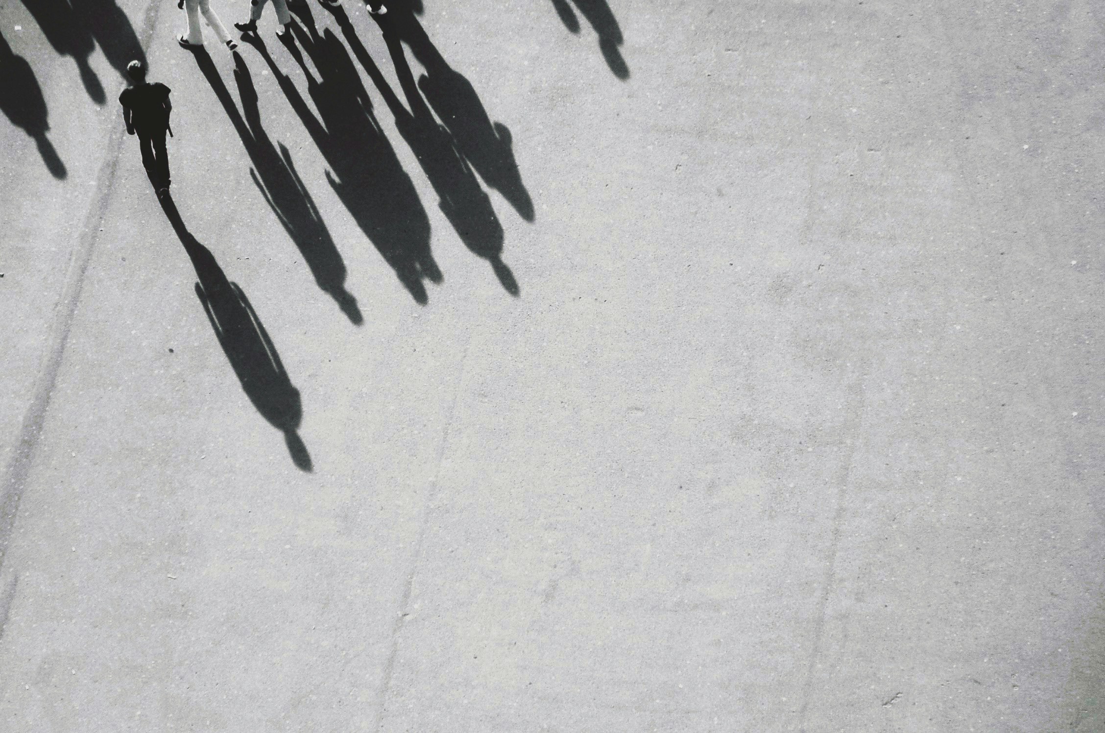 grayscale photography of shadow of people walking