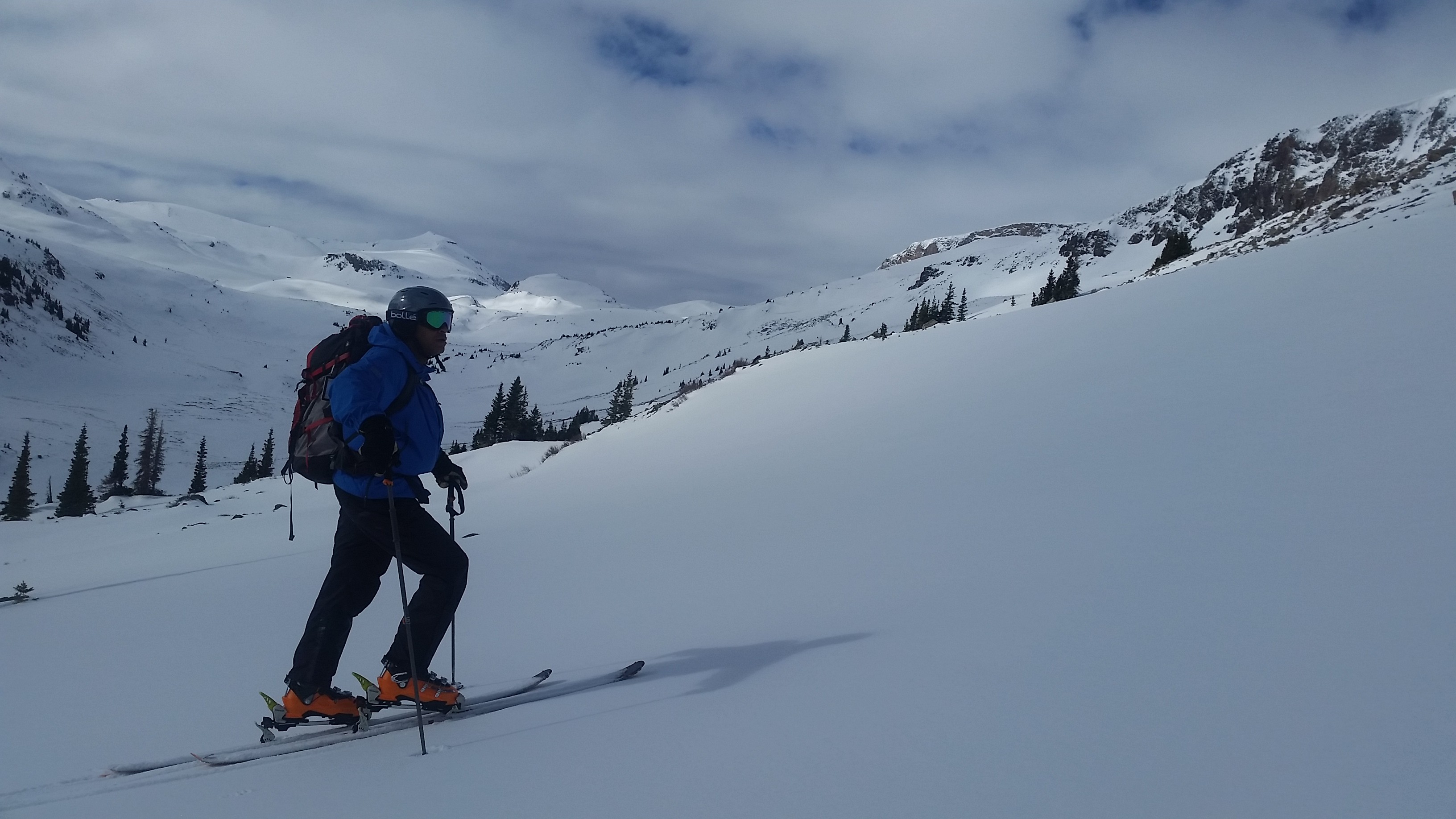 Skier ascends snow slope with mountains in the background