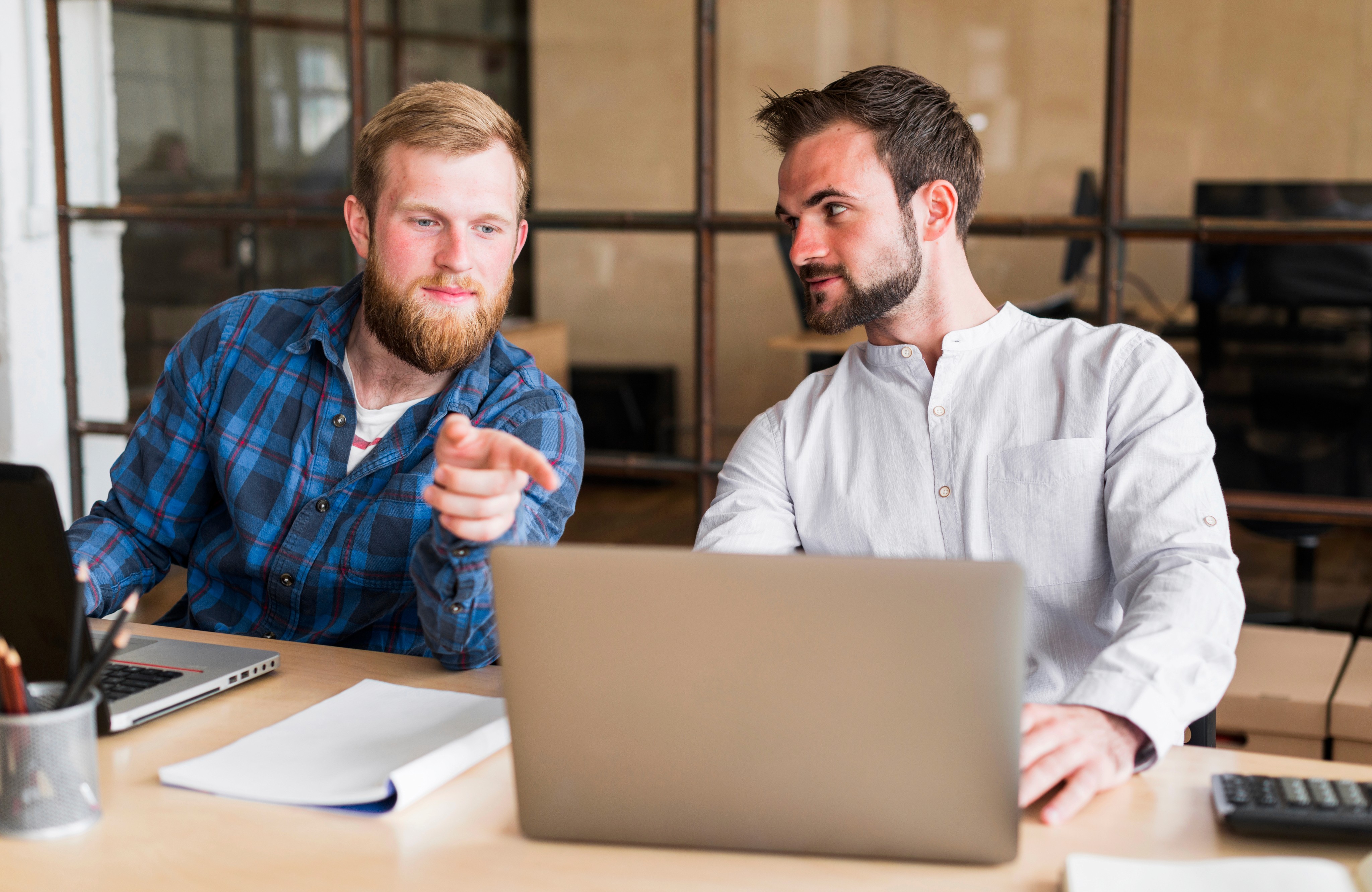Two men discussing something while looking at a laptop.