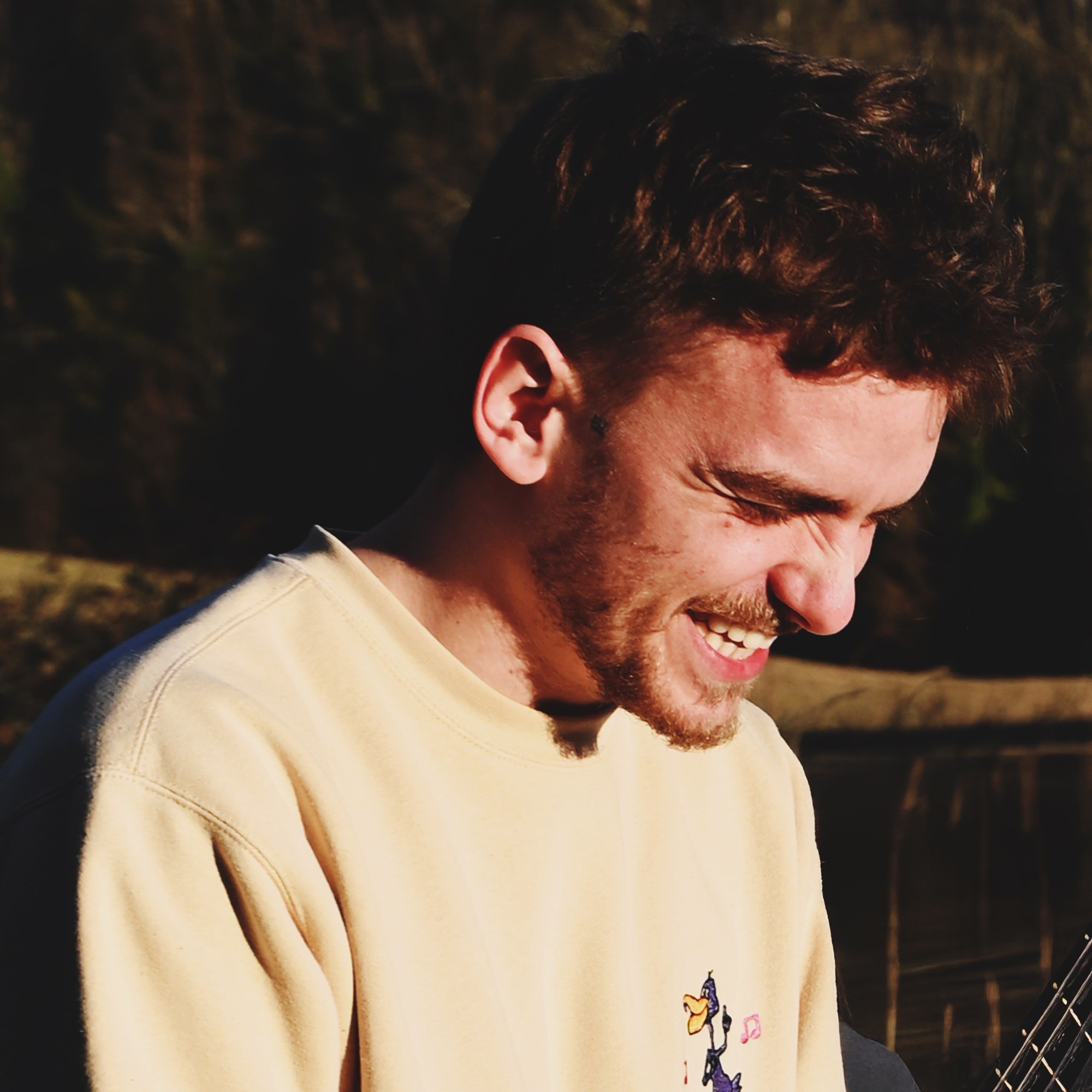 A thoughtful young person with dark hair gazes to the side, captured in soft black and white lighting.
