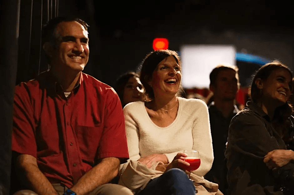 A couple smiling and clapping at a comedy show