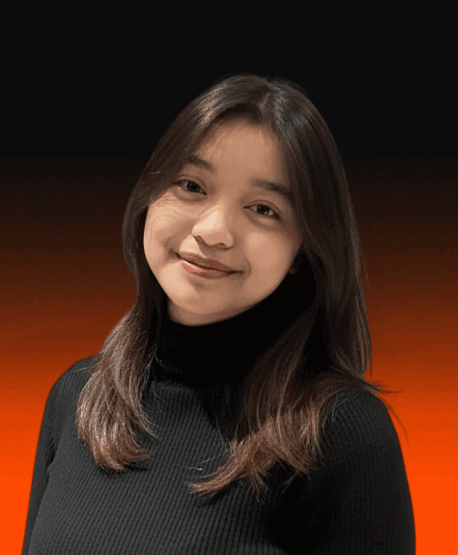 A man with curly hair smiling in a field of yellow flowers at sunset.