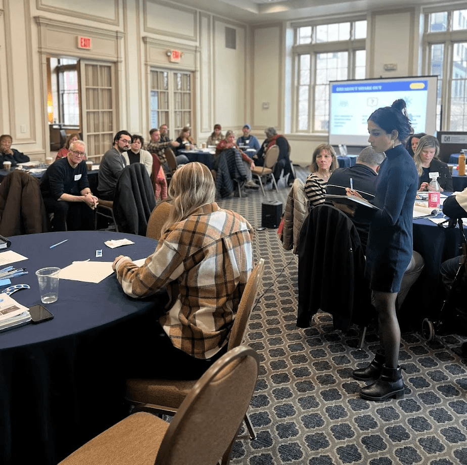 Modern home office setup with a monitor, ergonomic chair, keyboard, and indoor plants near a window with blinds.