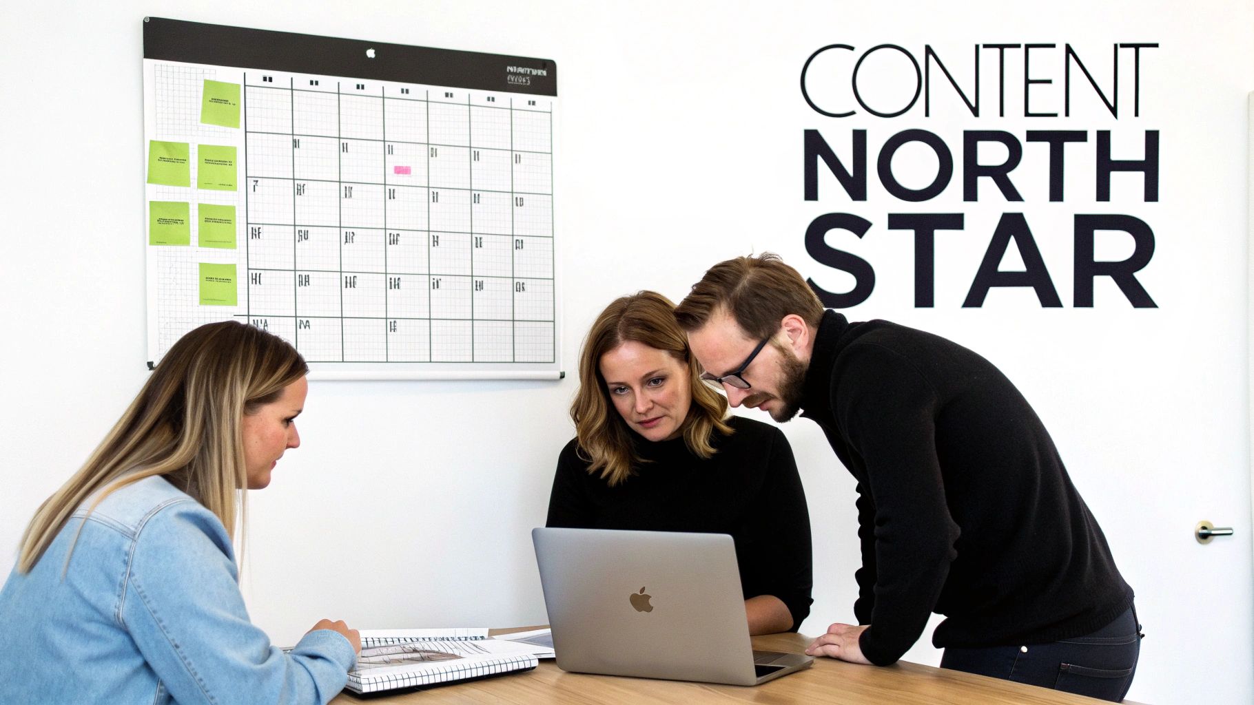 Three colleagues collaborate around a laptop and a content calendar whiteboard, planning their content strategy.