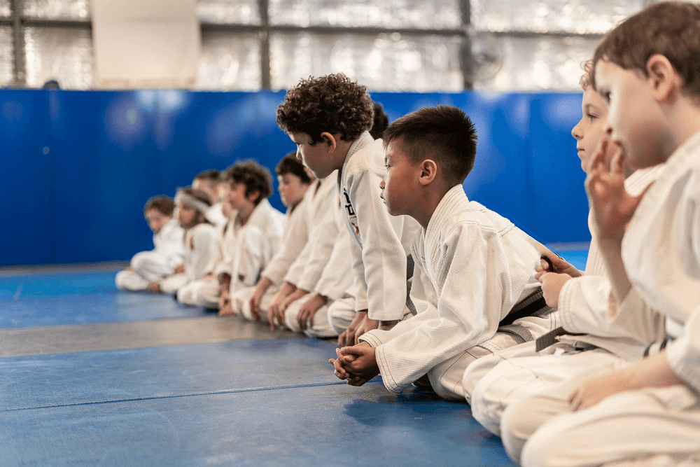 Kids practicing grappling techniques on blue mats