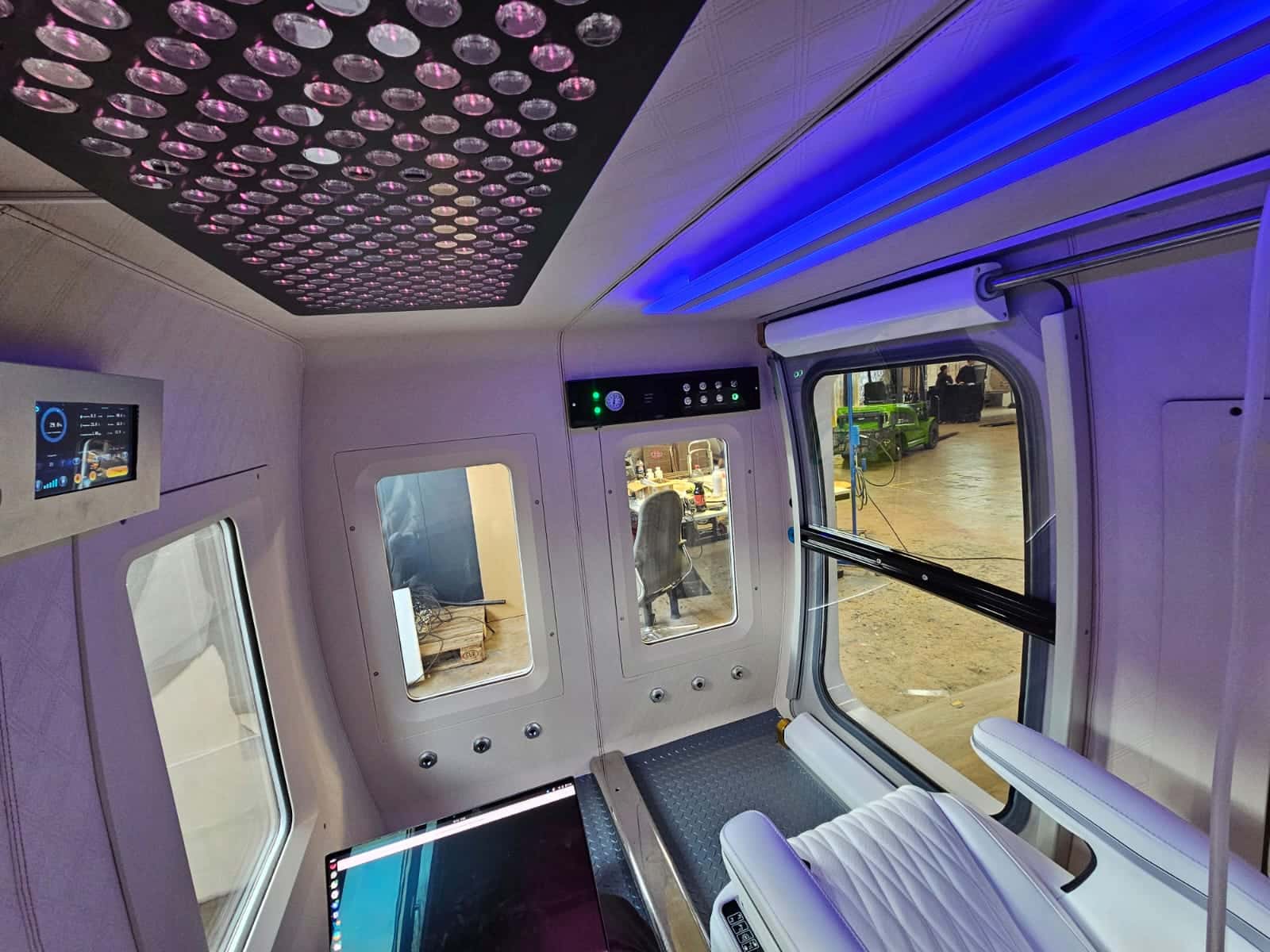 Geräumiger Innenraum der X4OXYGEN Mehrpersonen-Kabine mit ergonomischen Sitzmöglichkeiten, LED-Lichtsteuerung und internem Display zur Überwachung der Kabinenatmosphäre während der Anwendung.