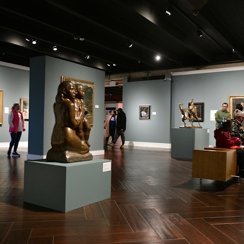 Pohled na galerii Schering-Plough s sochami a uměleckými díly a několika hosty prohlížejícími si exponáty