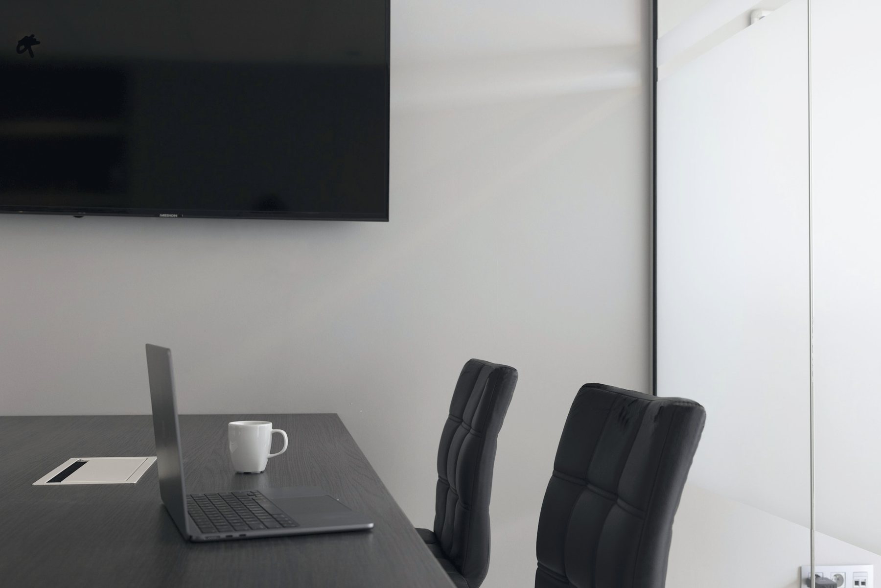 A small meeting room with a wall screen and a laptop