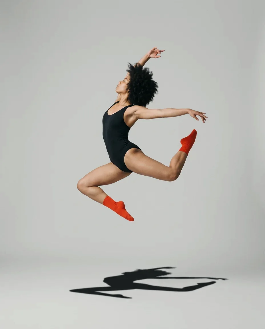 Dancer frozen mid-leap against a pale studio backdrop