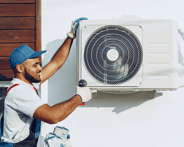 HVAC technician installing a heat pump system on an exterior wall