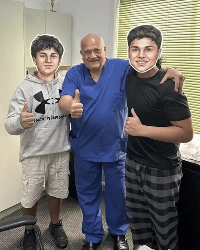 Dr. Ashraf Saddik giving a thumbs up with two teenage patients at his Melbourne clinic.