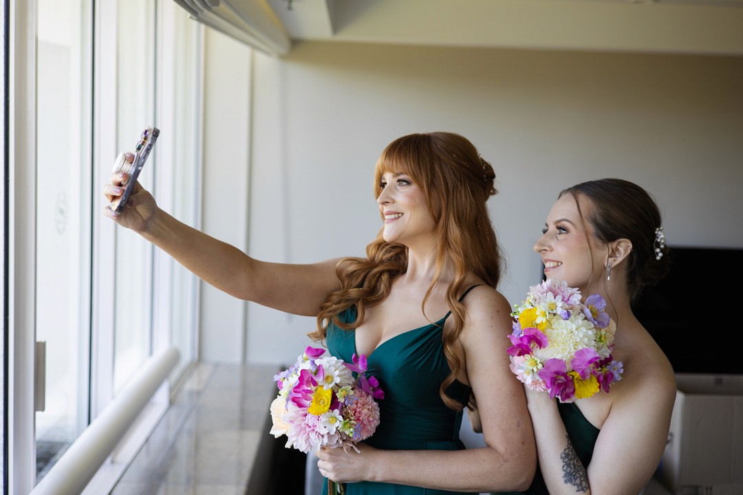 Bridesmaids taking selfies with bouquets