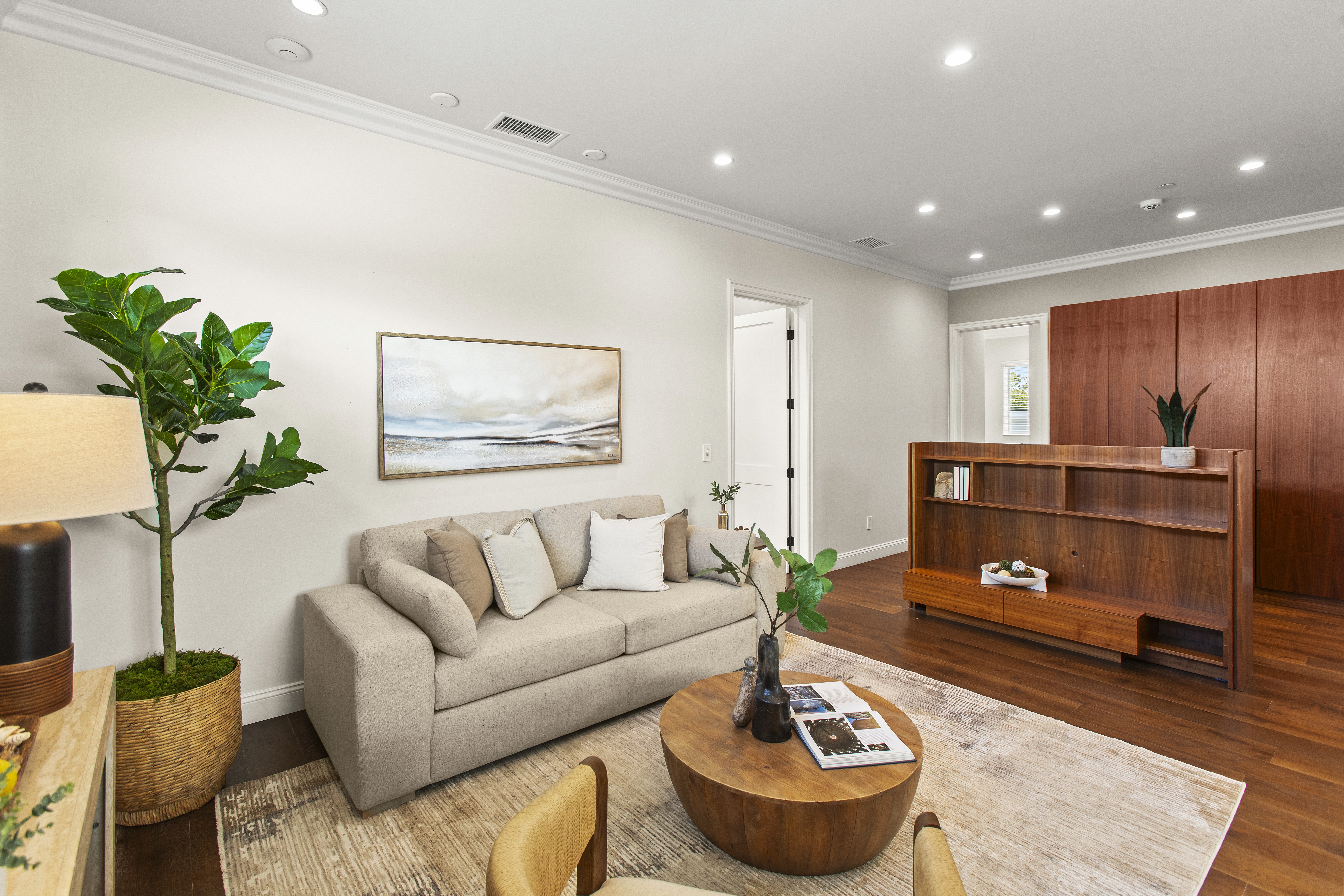 Professionally staged living room with a round mirror over the fireplace