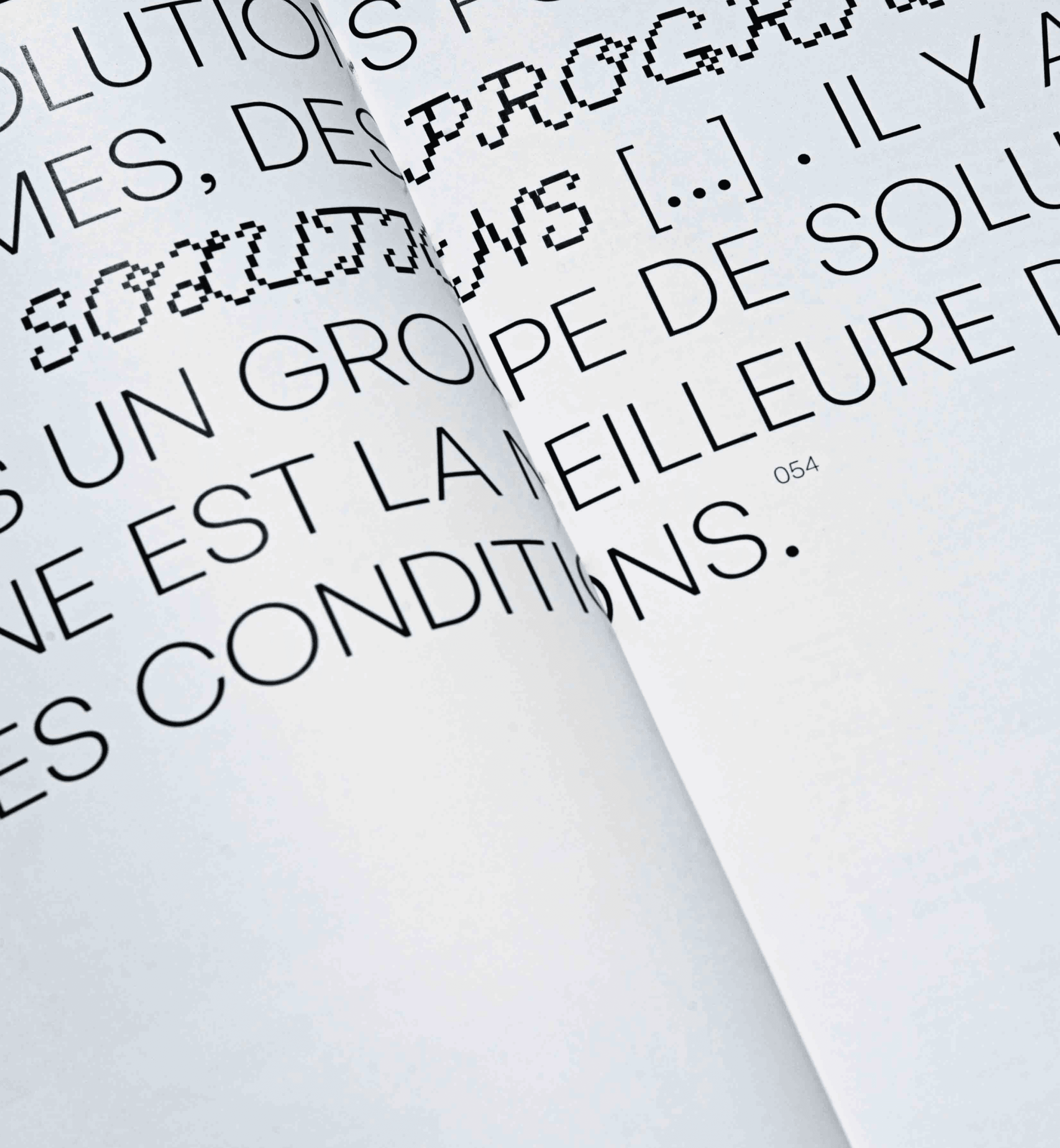 Editorial layout design featuring bold pixel-inspired typography in large black letters across white pages