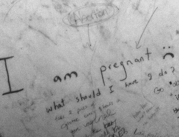 The image shows a gray surface with black handwritten text. The central focus is the phrase "I am pregnant" written in a cursive style. Below it, other text reads "what should I have to go through?" and includes phrases like "take a pill of" and "go through." A downward arrow points to the word "Abortion," and another arrow points to the phrase "2 do?". The overall appearance suggests a personal journal entry or note related to pregnancy and abortion.