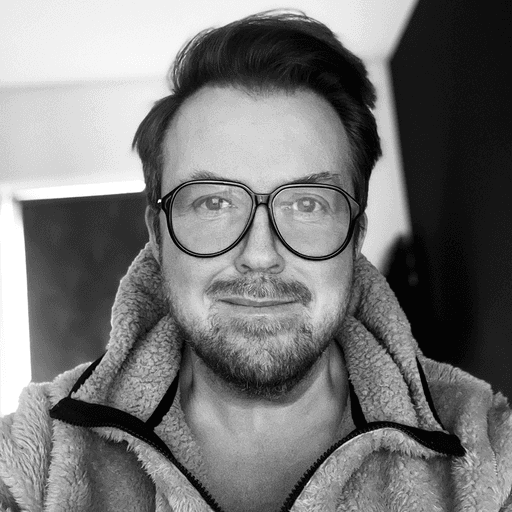 A thoughtful young person with dark hair gazes to the side, captured in soft black and white lighting.