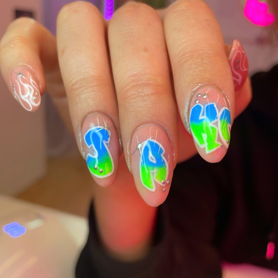 Oval nails with an earthy 70s palette—olive green, burnt orange, and cream—featuring abstract geometric blocks and retro "lava lamp" shapes in teal.