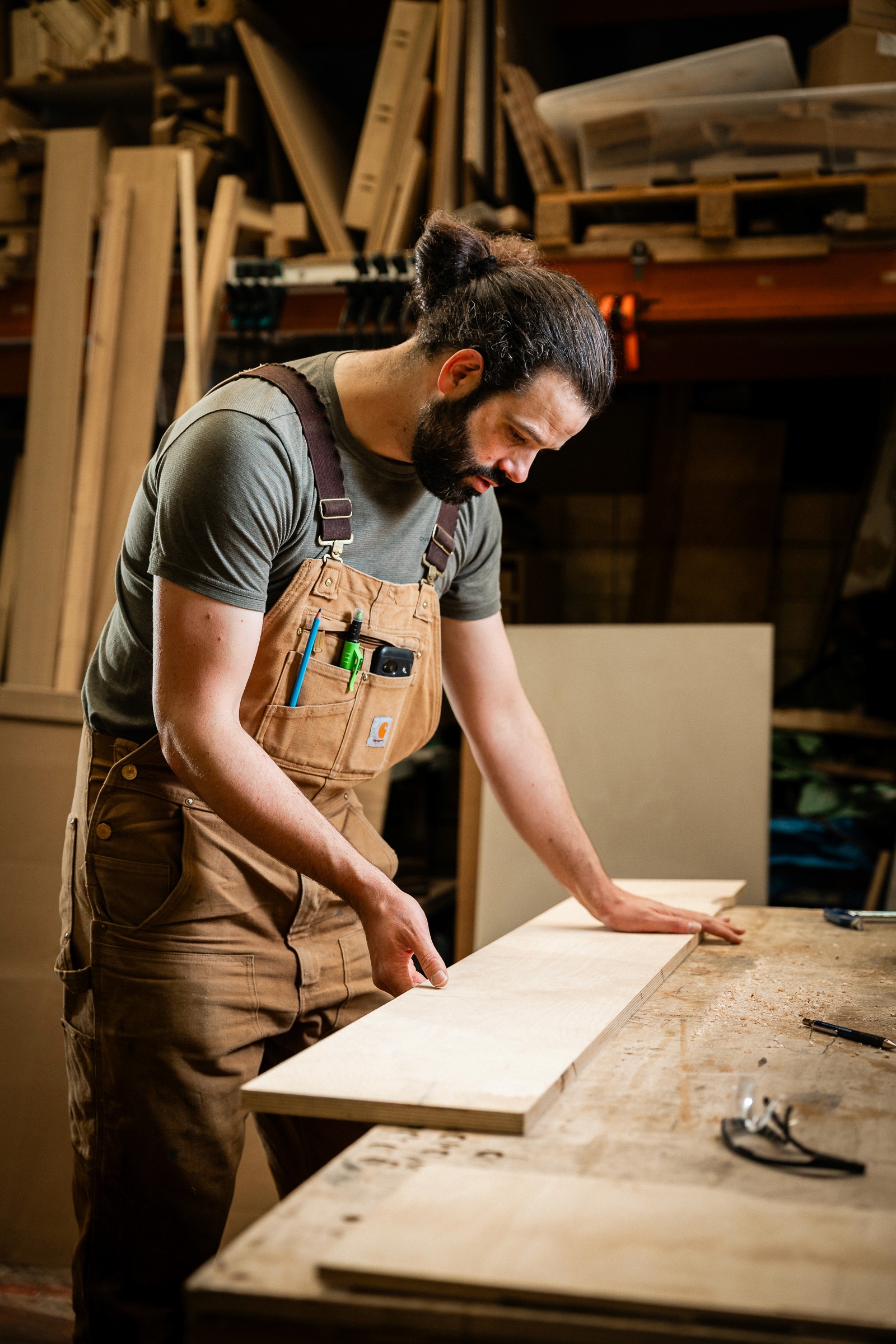 ontwerper en meubelmaker teun van den neste inspecteert een houten plank in een houtatelier in brussel