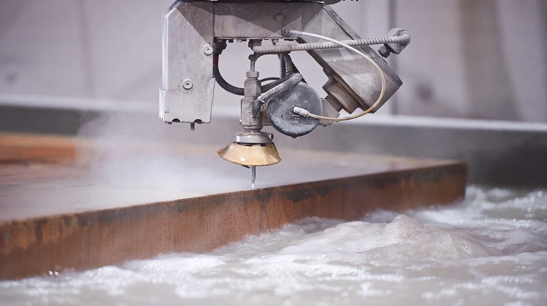Waterjet cutting head slicing through thick steel plate using high-pressure waterjet technology.
