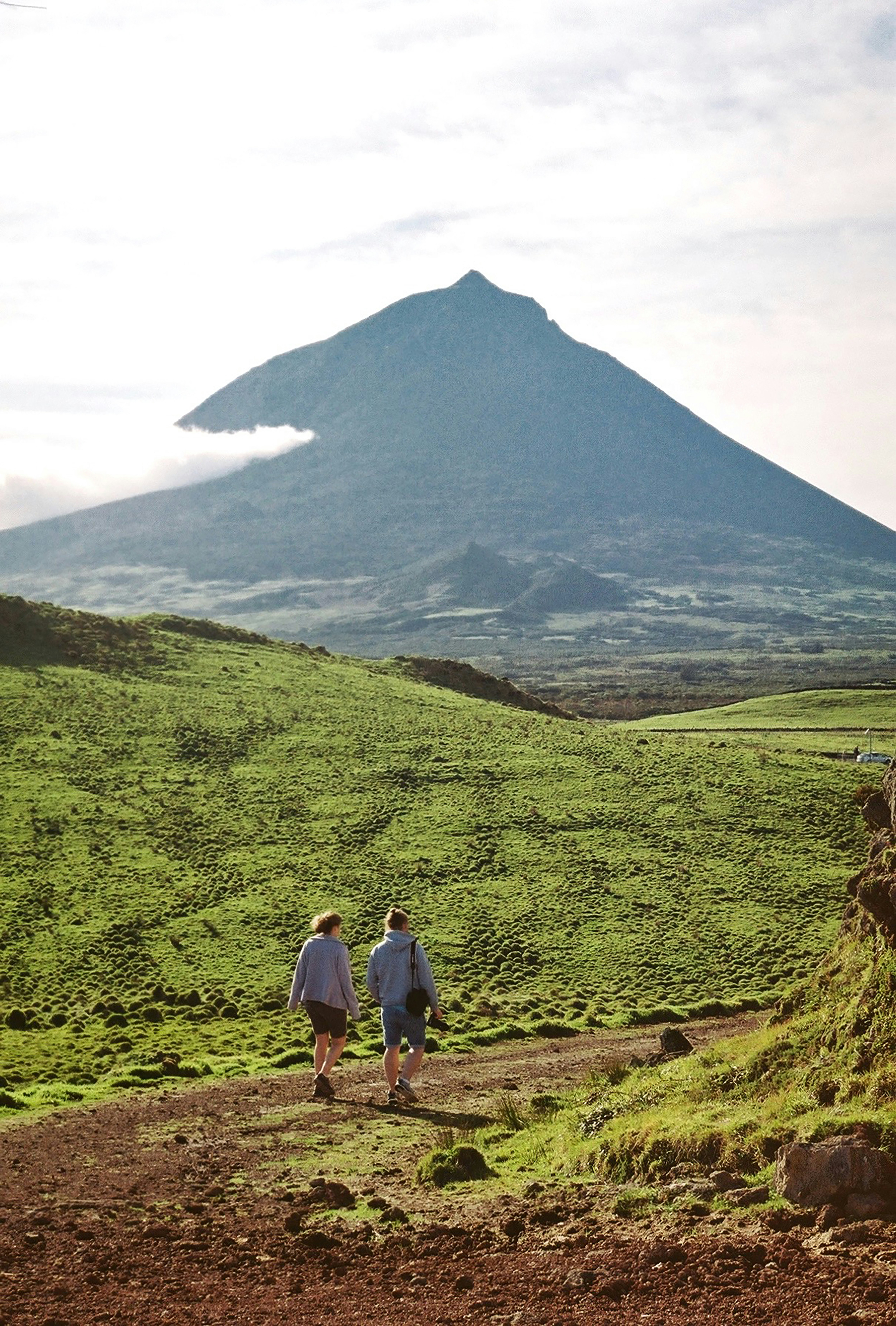 A wide green hill with two people walking