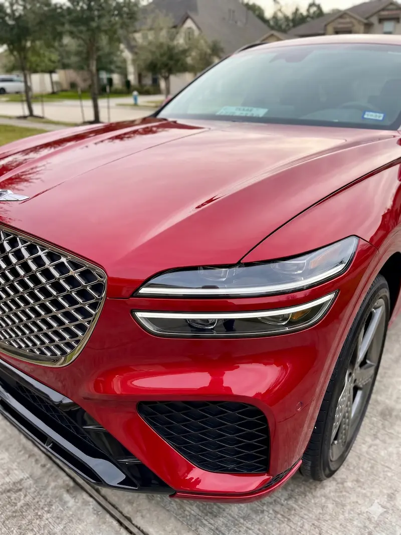 Mobile headlight restoration service in Houston featuring a red Genesis GV70 with clear, polished headlight lenses.