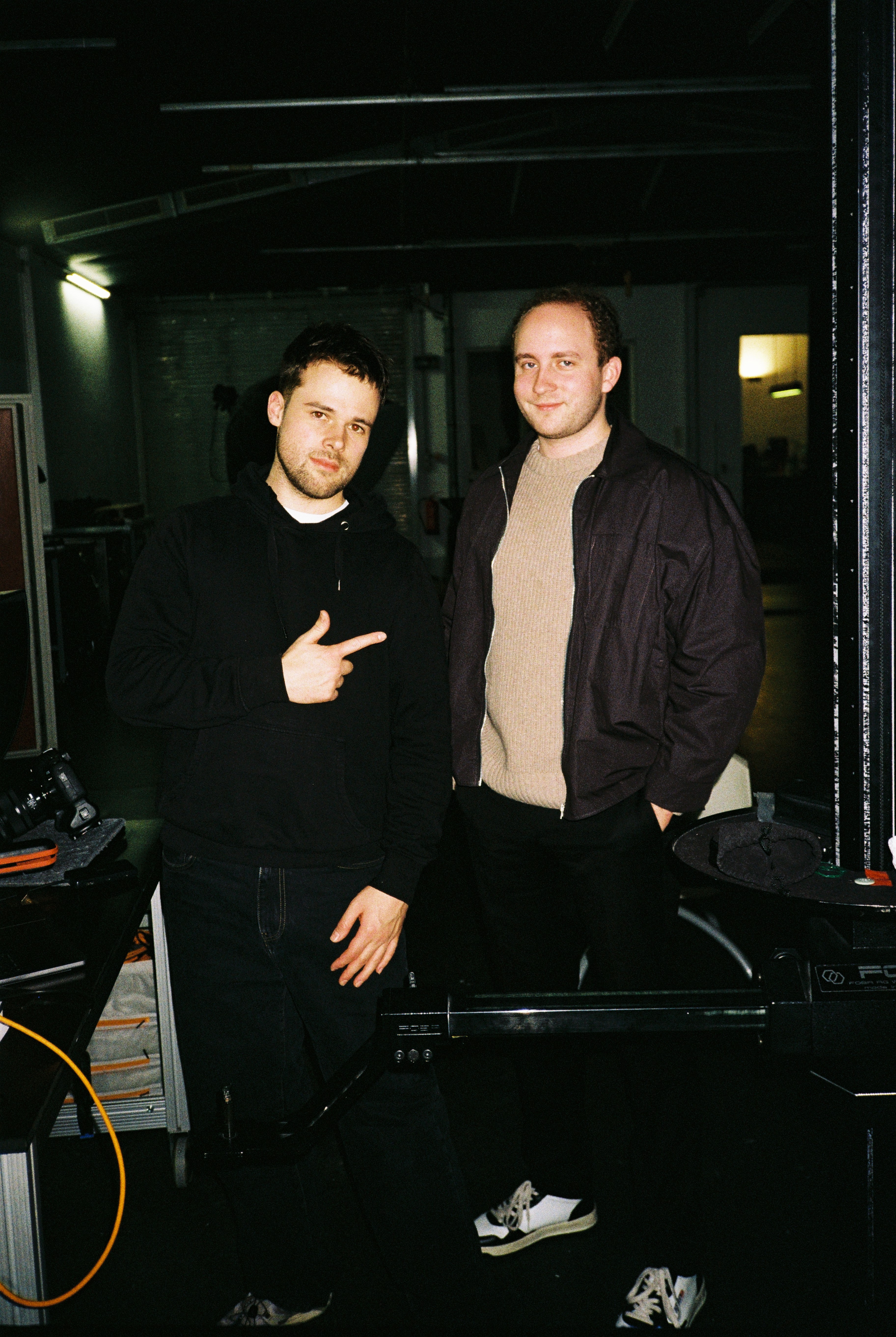 A young woman with long dark hair smiles confidently while crossing her arms in a modern indoor setting.