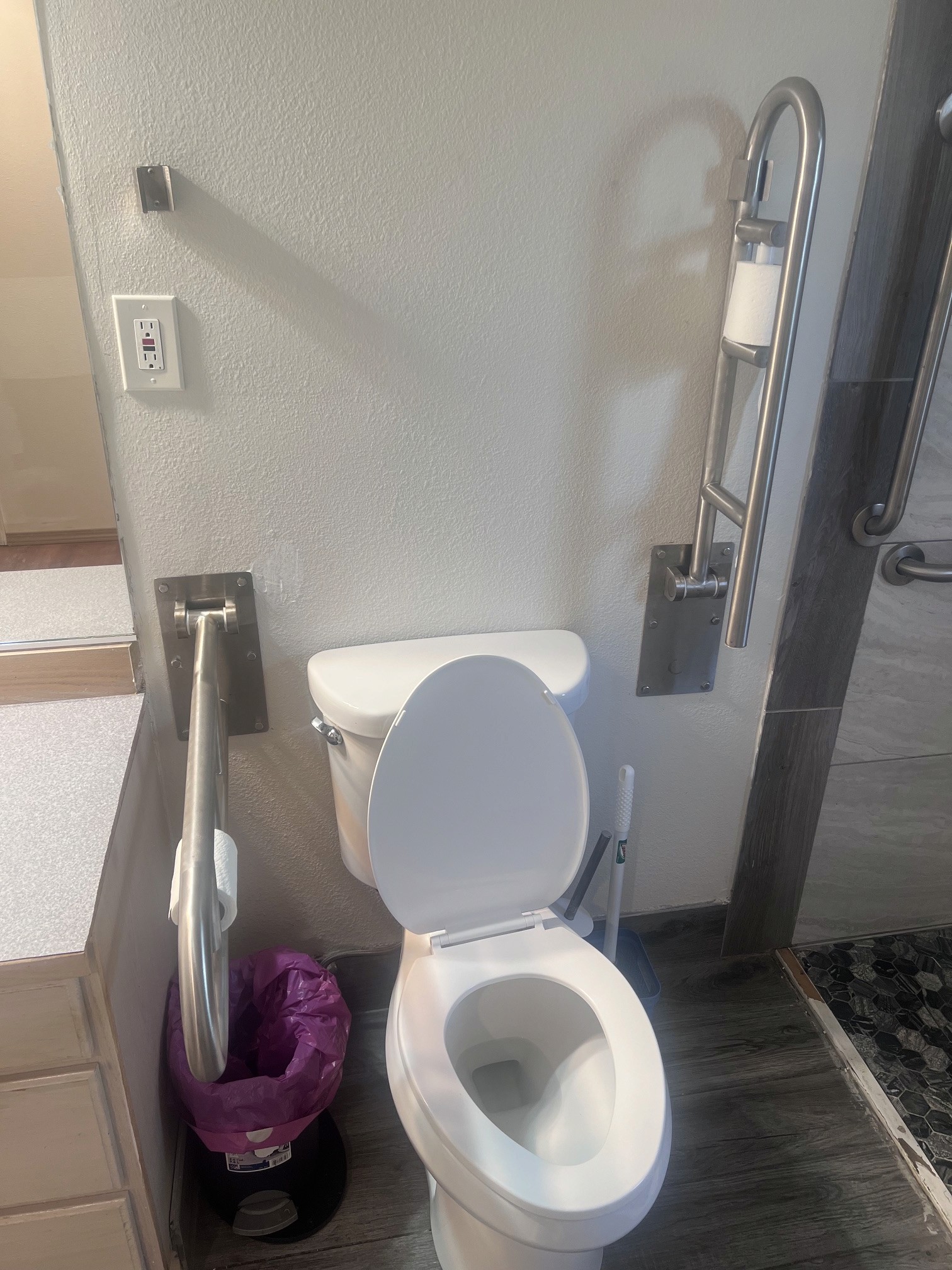 Toilet with fold-down stainless support rails on both sides and a raised seat