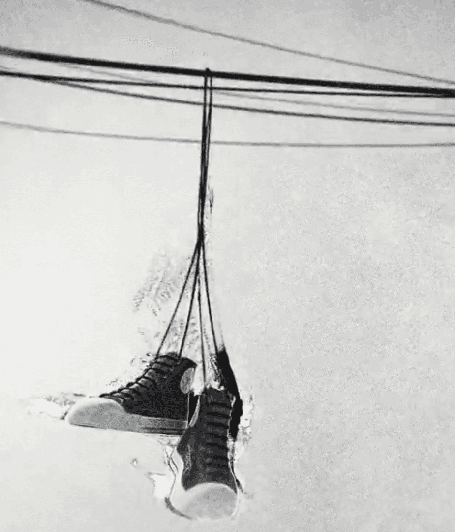 Black high-top Converse sneakers hanging from power lines in hand-drawn animation style, celebrating the brand’s 100-year cultural legacy.