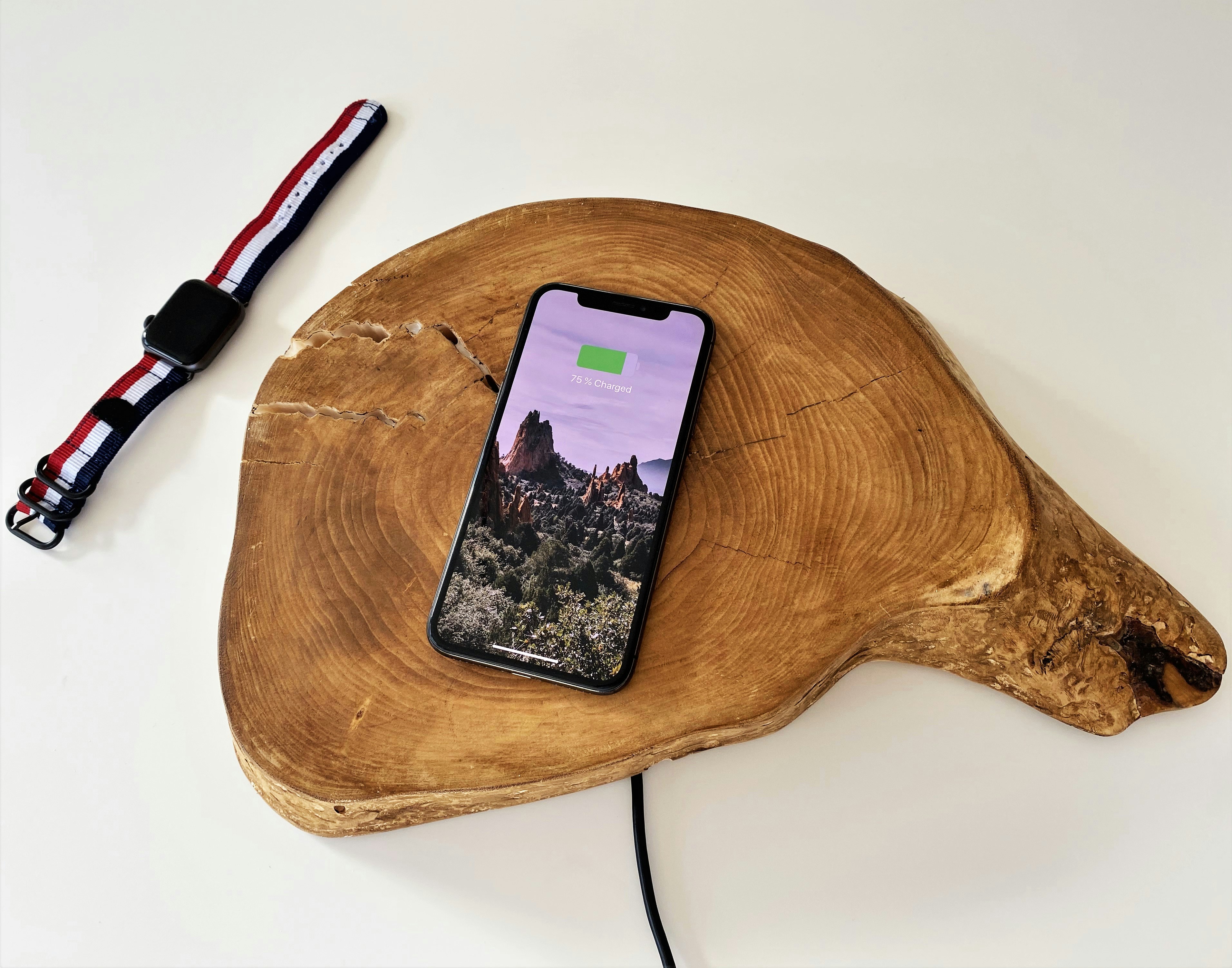 Apple Watch and iPhone charging on a natural wood slab desk accessory