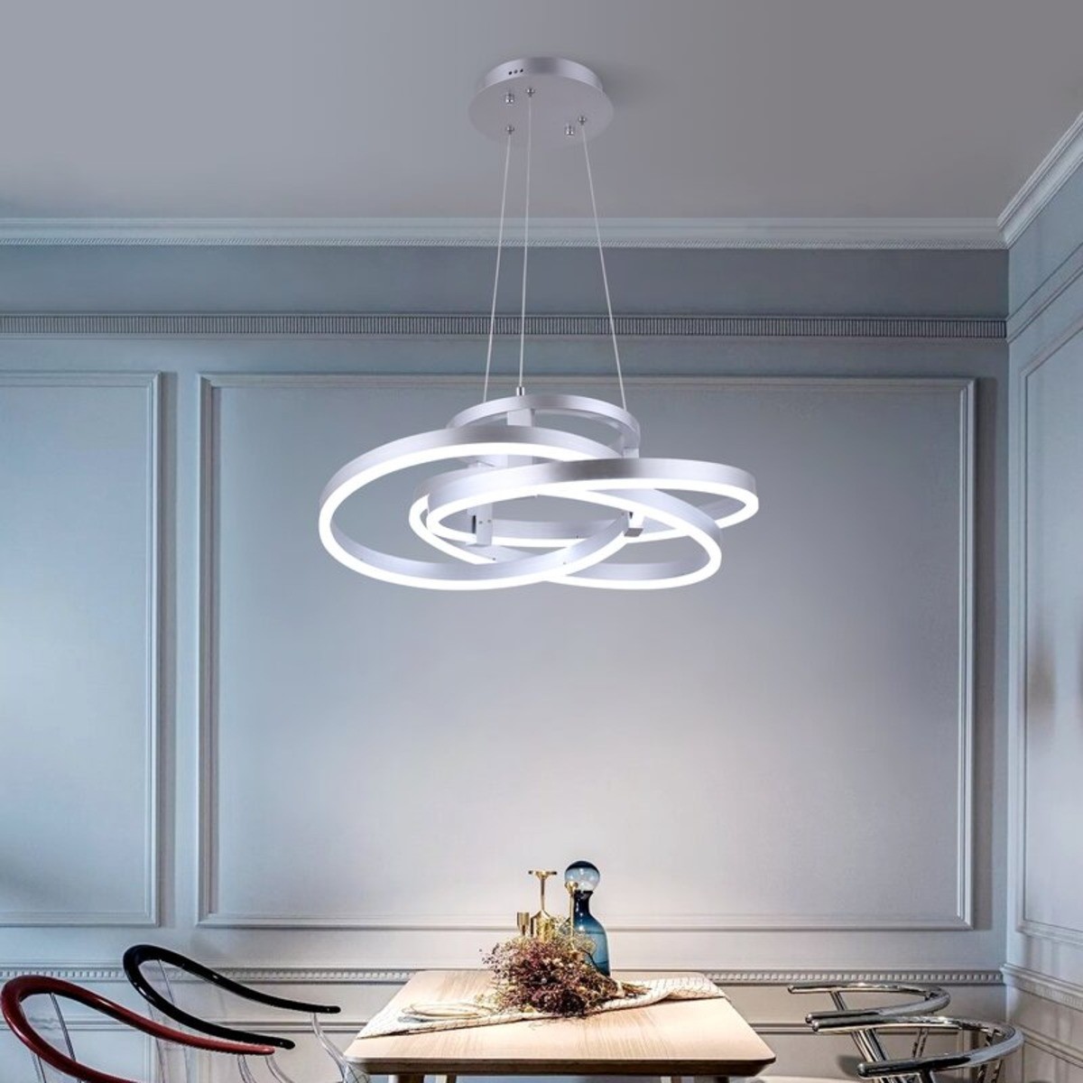 A white geometric chandelier hanging from the ceiling over a small rectangle dining table.